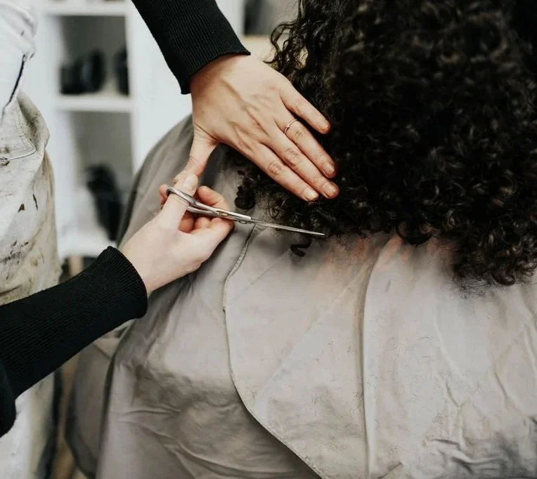 Siren stylist trimming curly hair ends with professional scissors during a precision curl cut at Siren Curl Studio in Tulsa.