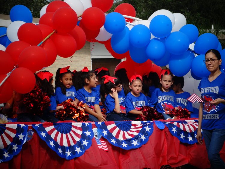 Children wearing patriotic colors riding on a decorated float during the Edinburg Veterans Day Parade.