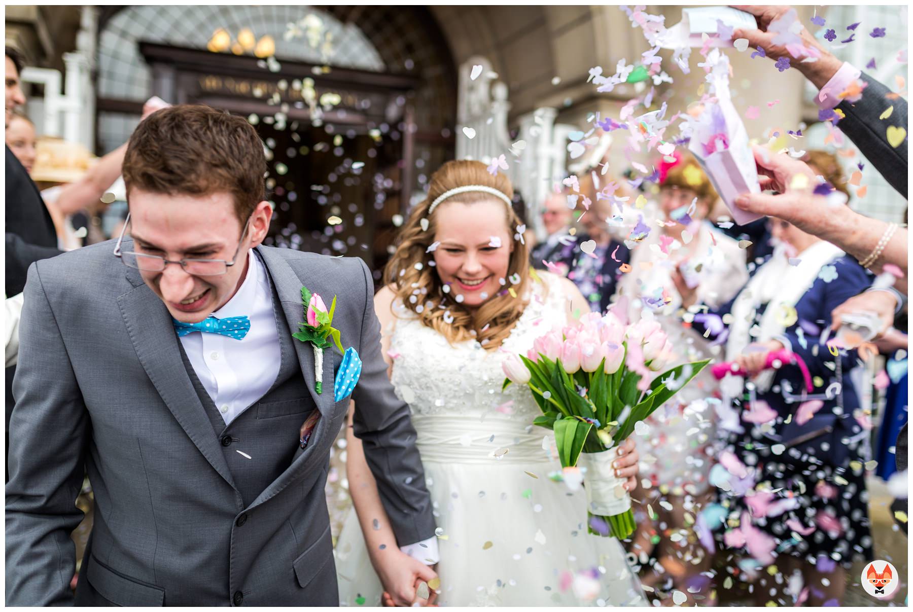 bride and groom run through confetti