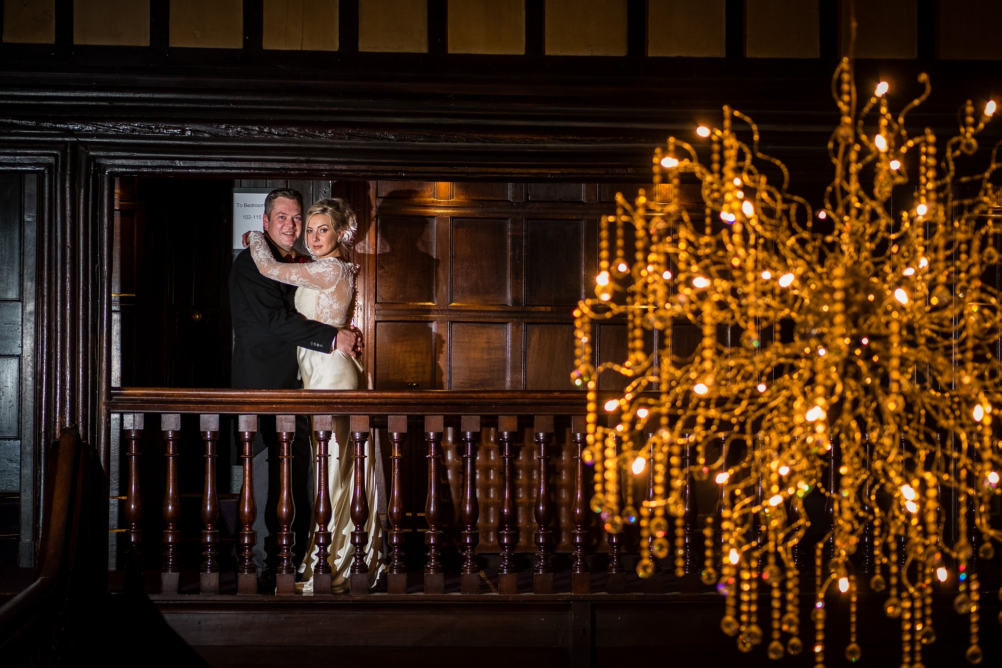 bride and groom in front of chandelier 