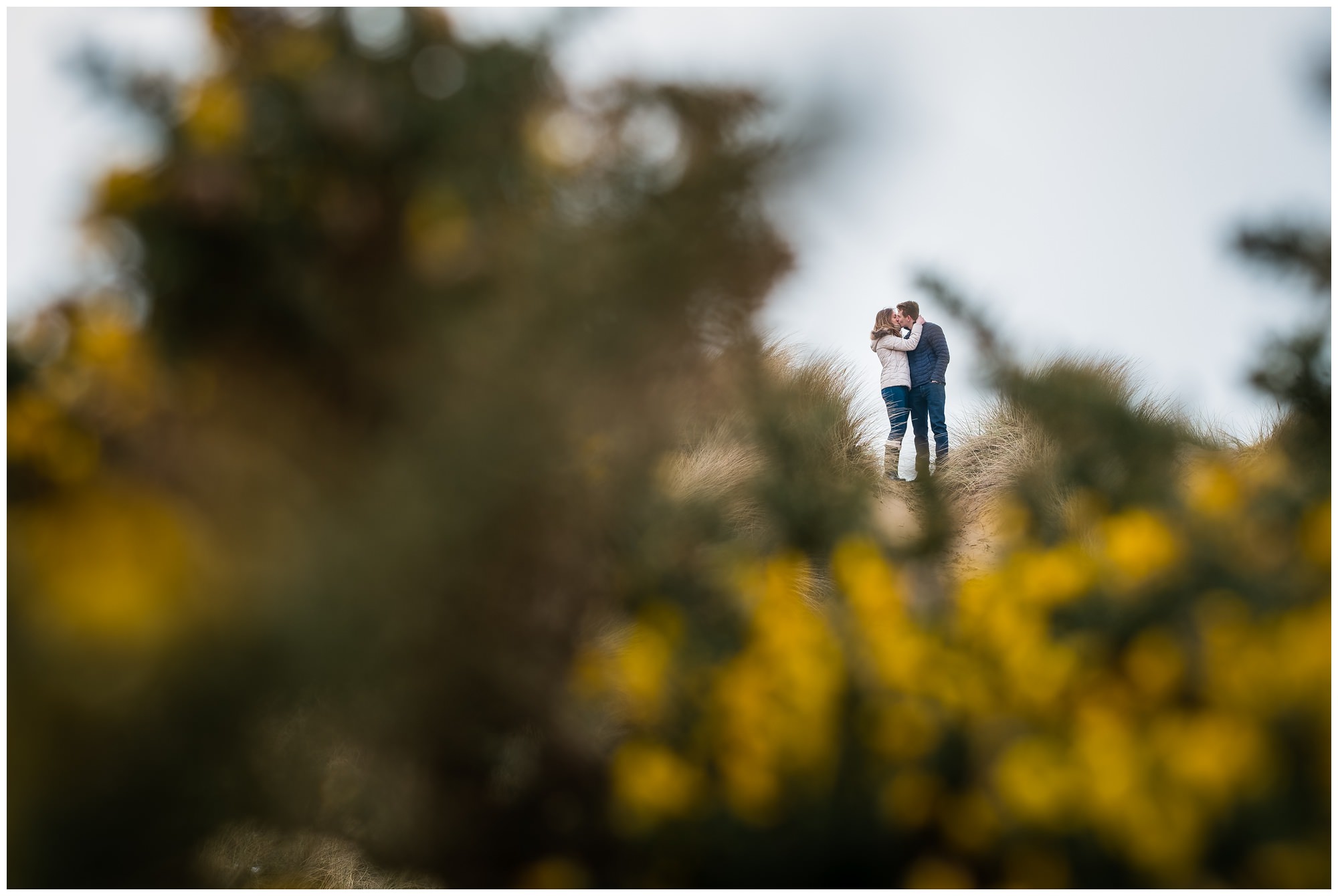 couple kissing between bushes