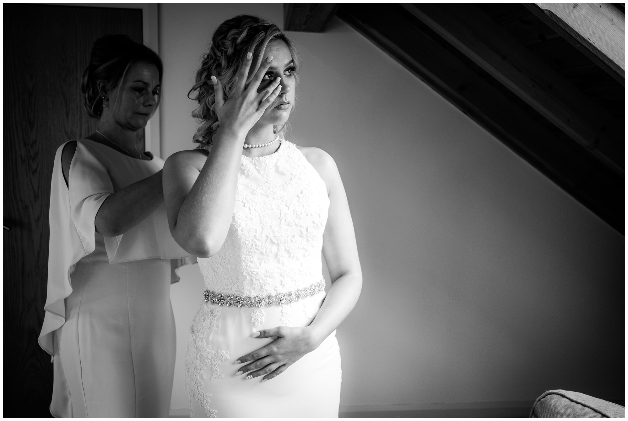 bride crying while mum fastens wedding dress