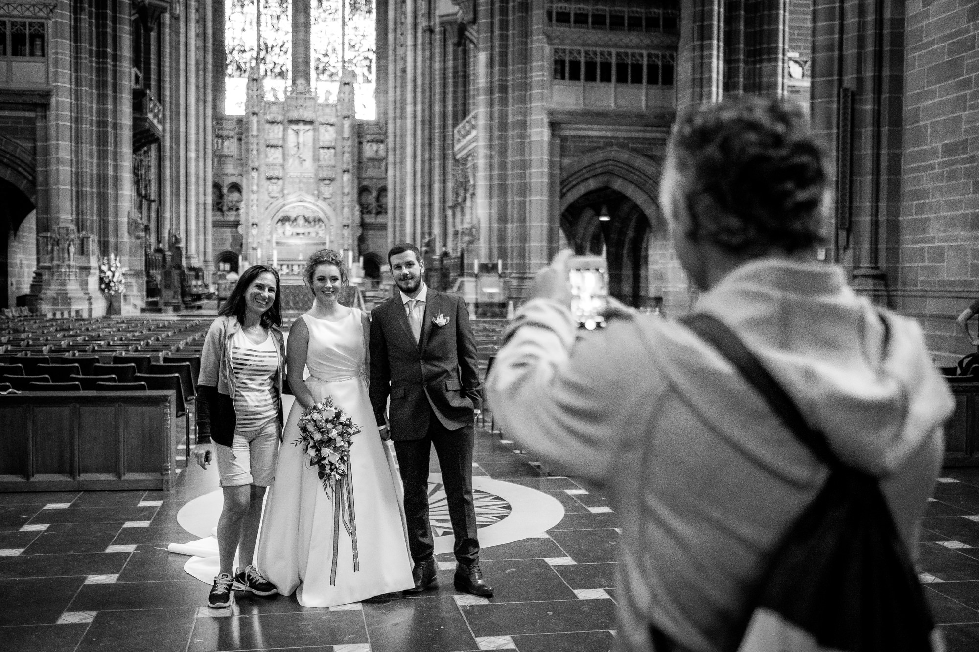 a tourist has photo taken with bride and groom