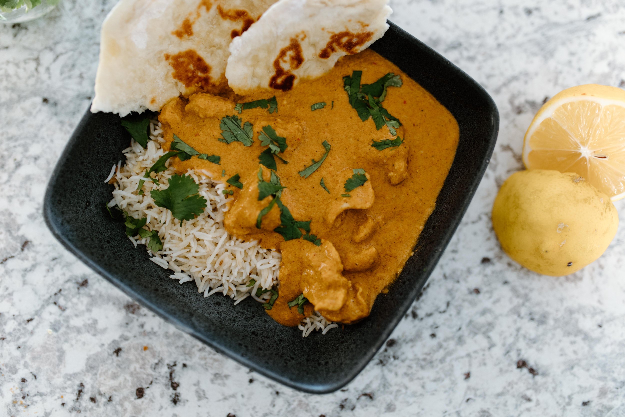 Plated slow cooker butter chicken with rice and naan.