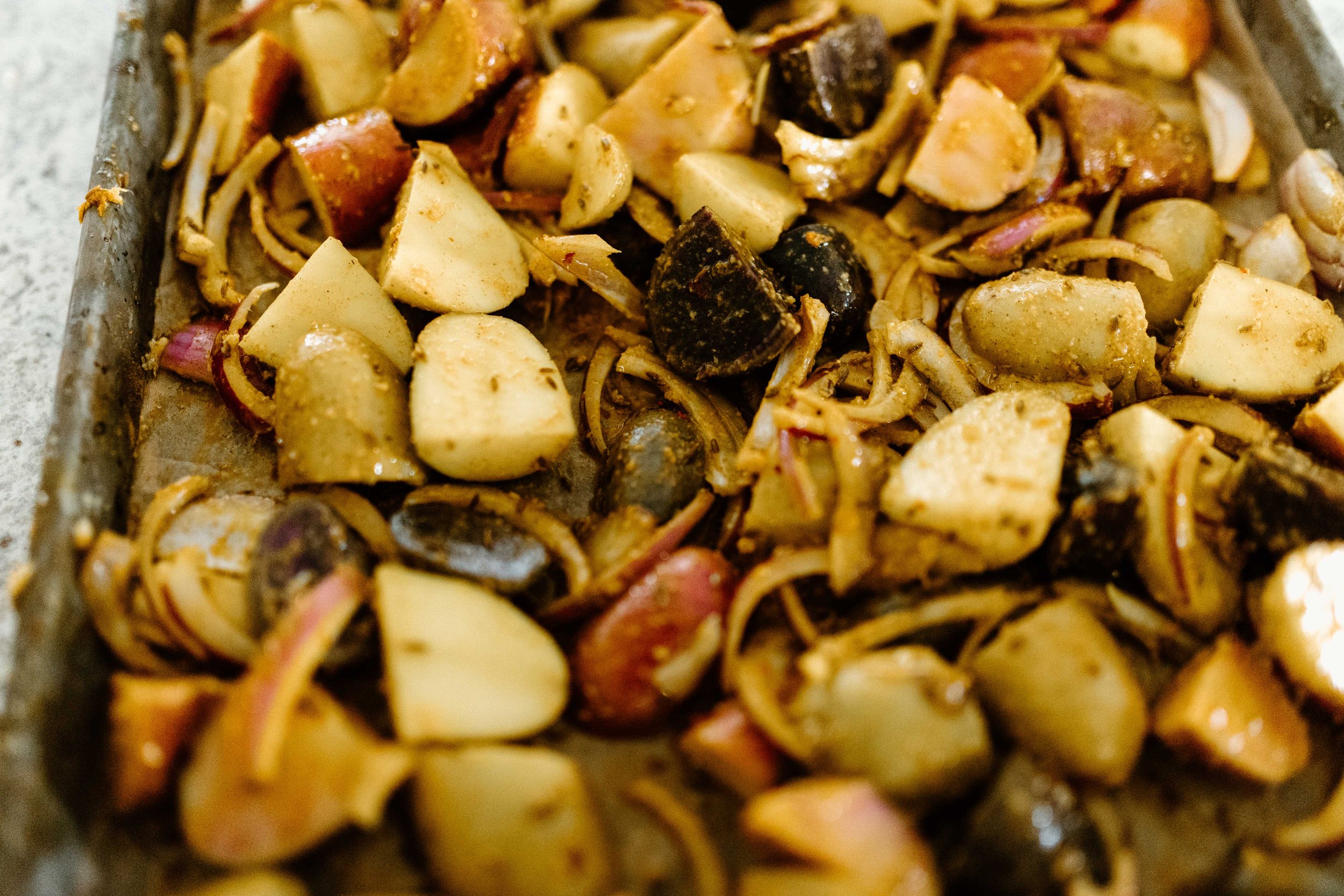 spices and oil go on the sheet pan aloo jeera potatoes