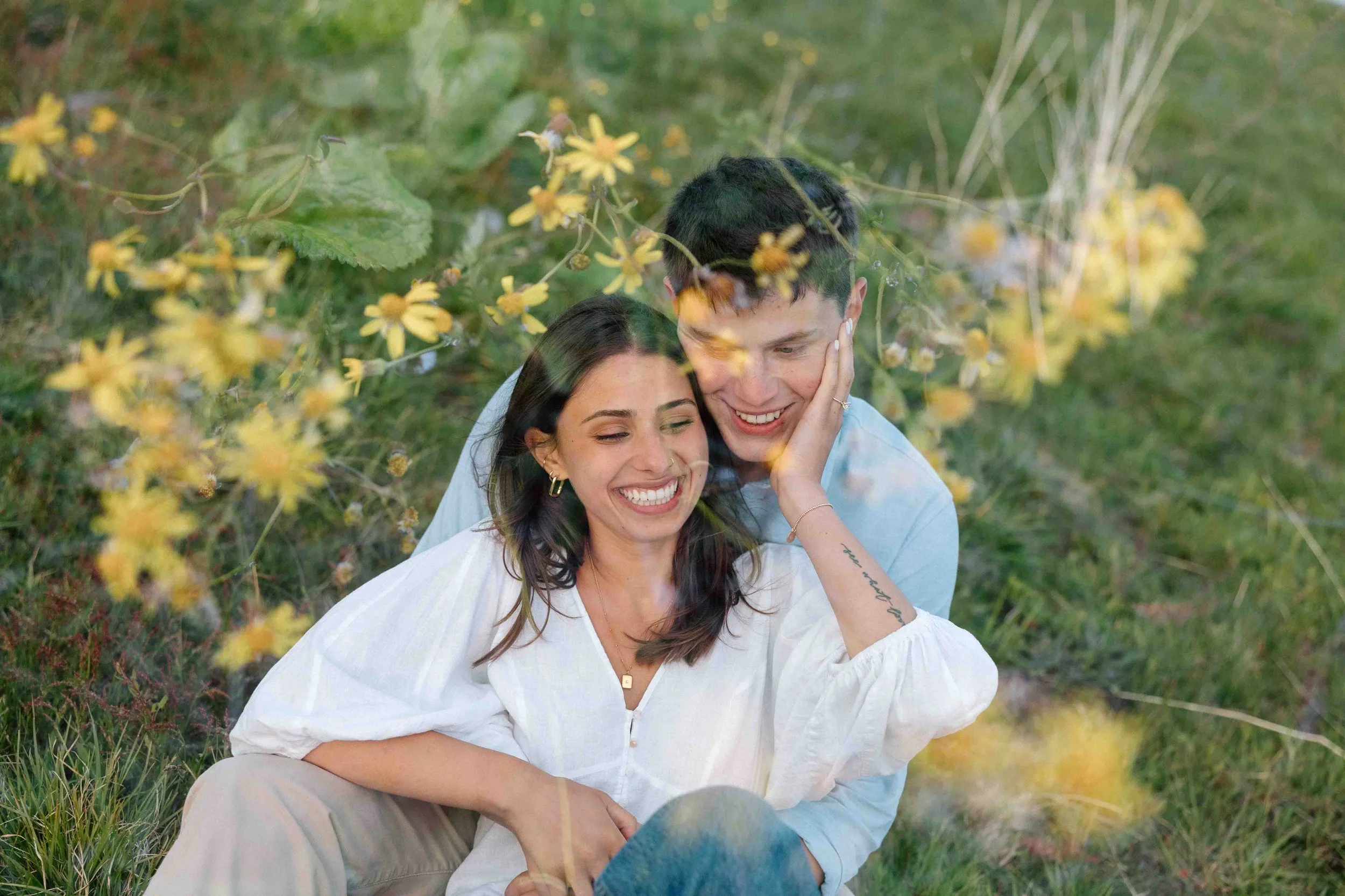 Engaged couple sits and smiles with yellow flower double exposure