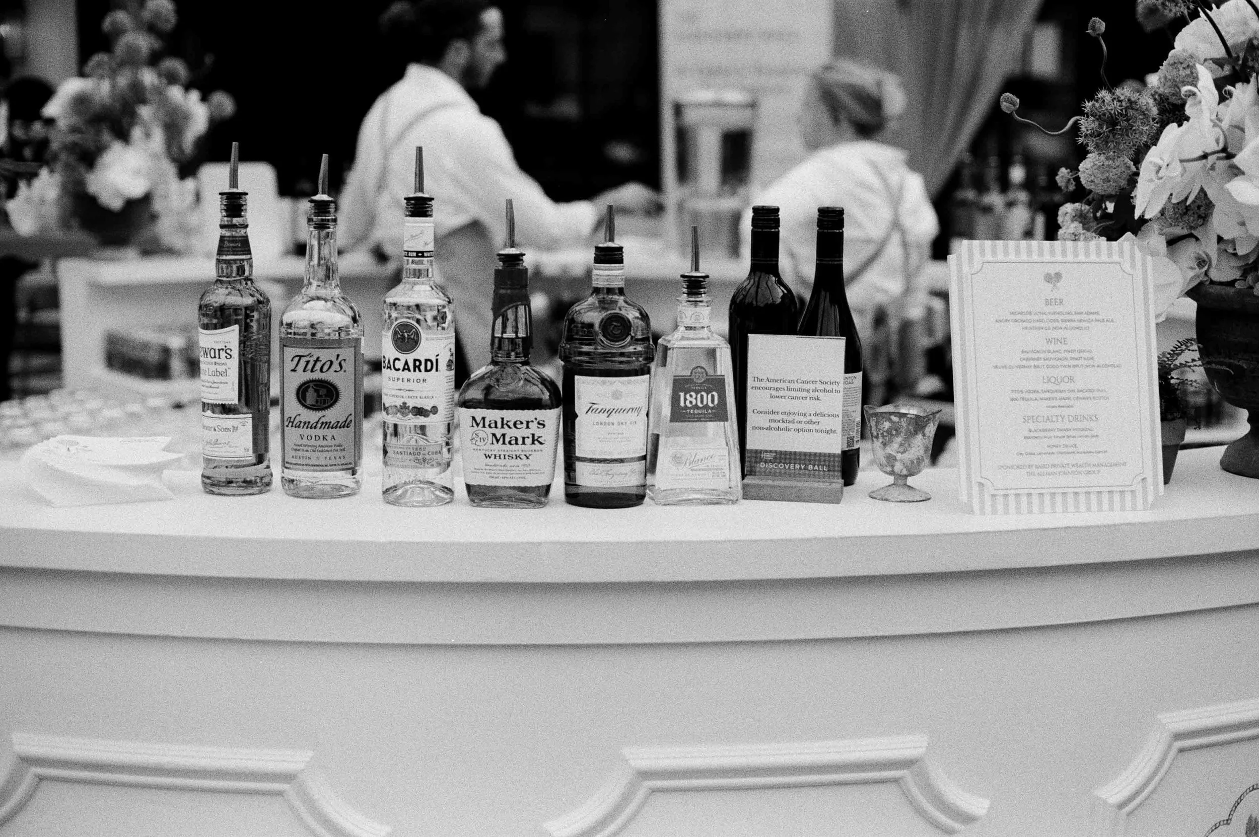 black and white film scan of bottles of liquor at a wedding reception