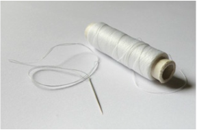 Photo of a spool of thread with a needle for sewing.