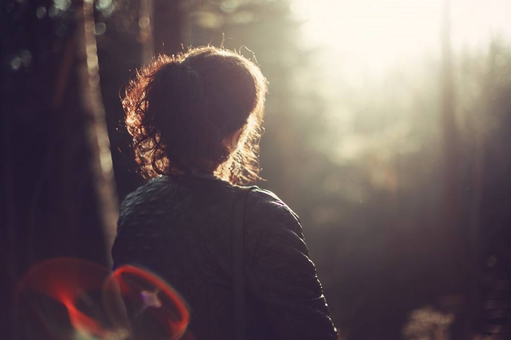 Woman sitting alone on bench in a forest reflecting on life and relationships