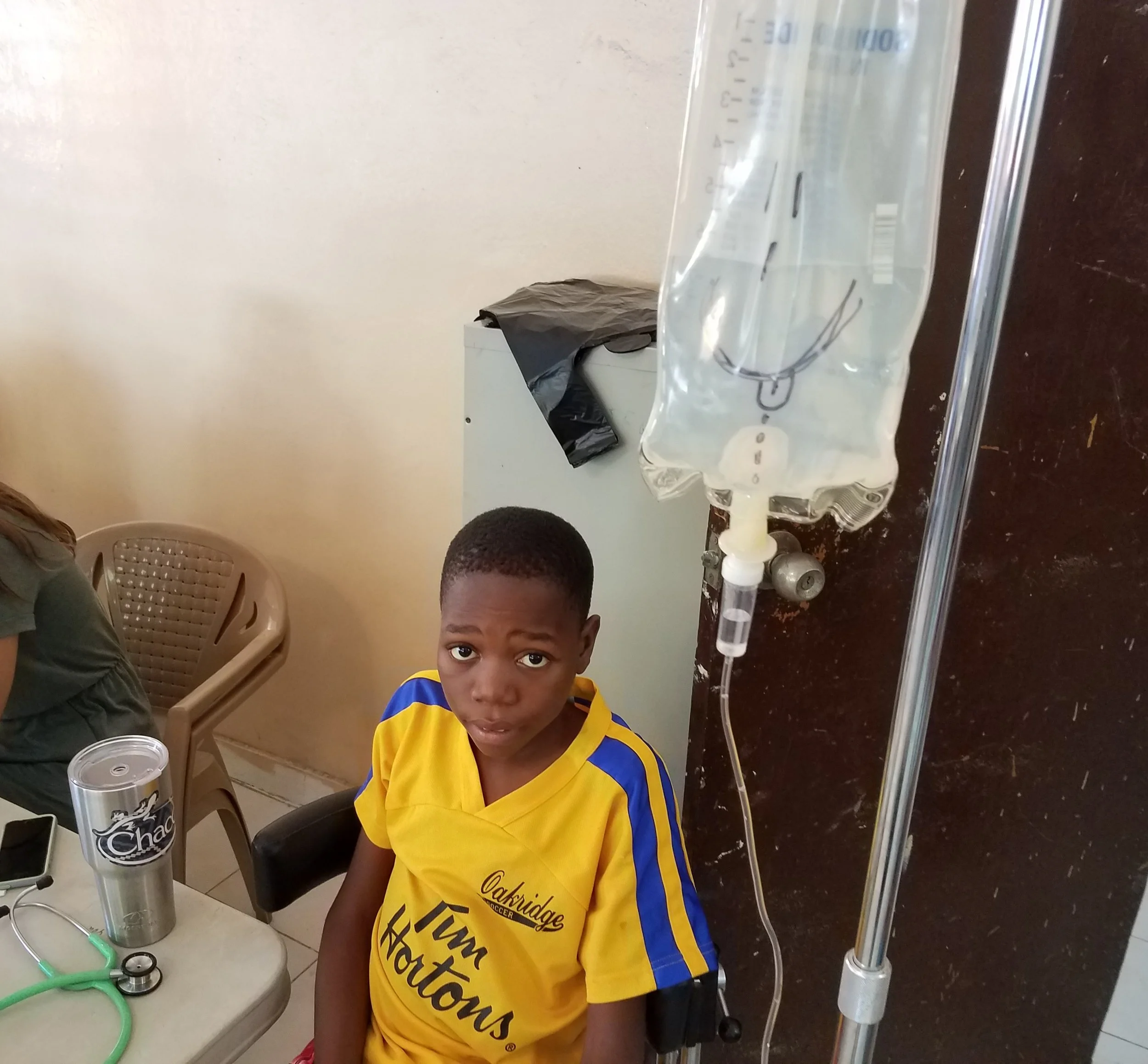 Jackenson getting a “Piki” during a Sickle Cell crisis but still wanting to be in the clinic. He didn't see the humor in my artwork on his IV bag.