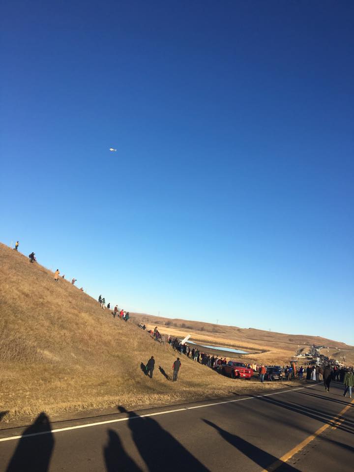 Spiritual leaders march to the pipeline while helicopters and drones circle overhead.