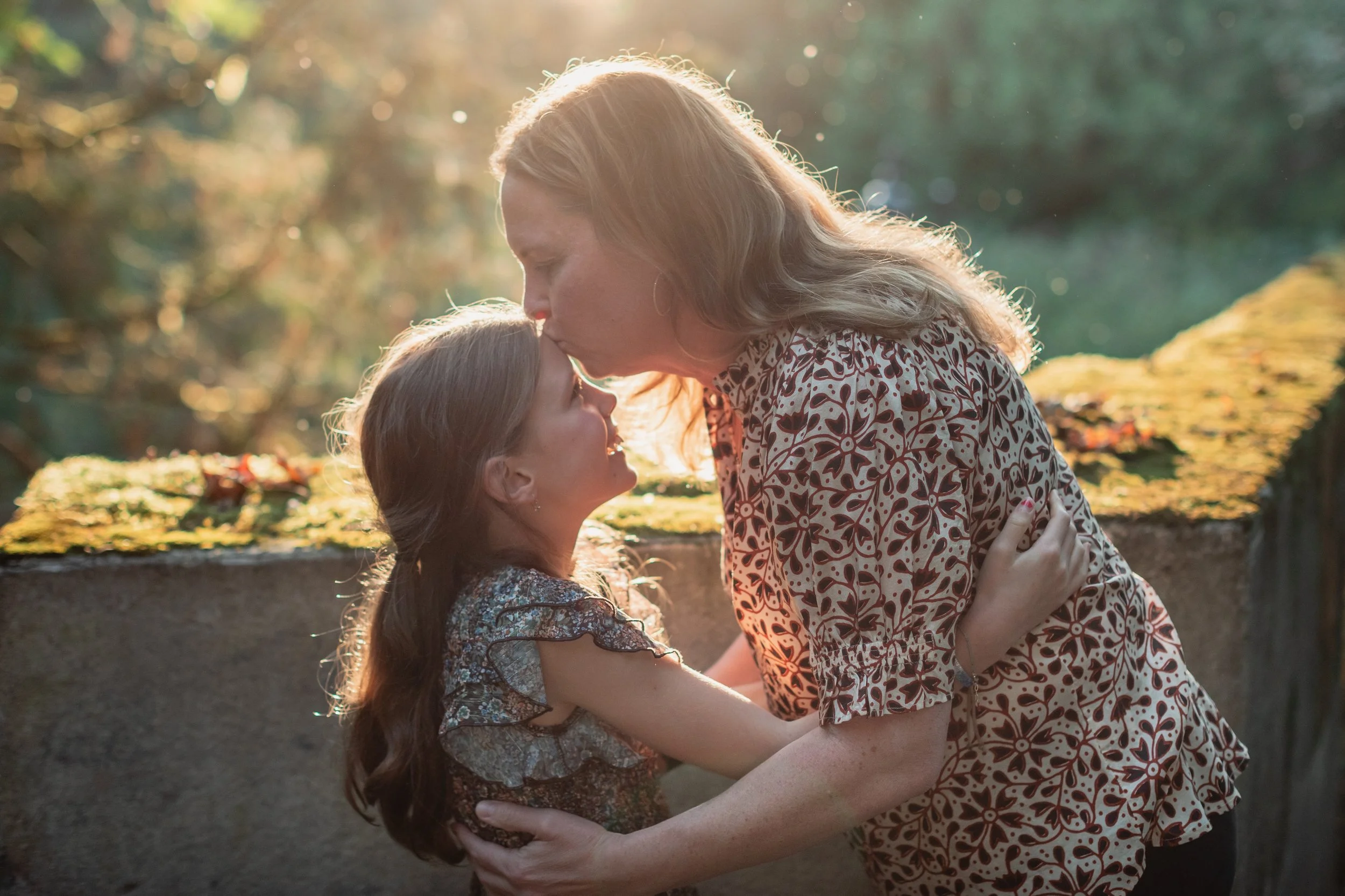Heartfelt mother-daughter moment at the Seattle Arboretum. Seattle family photography featuring warm backlight and lush green foliage.