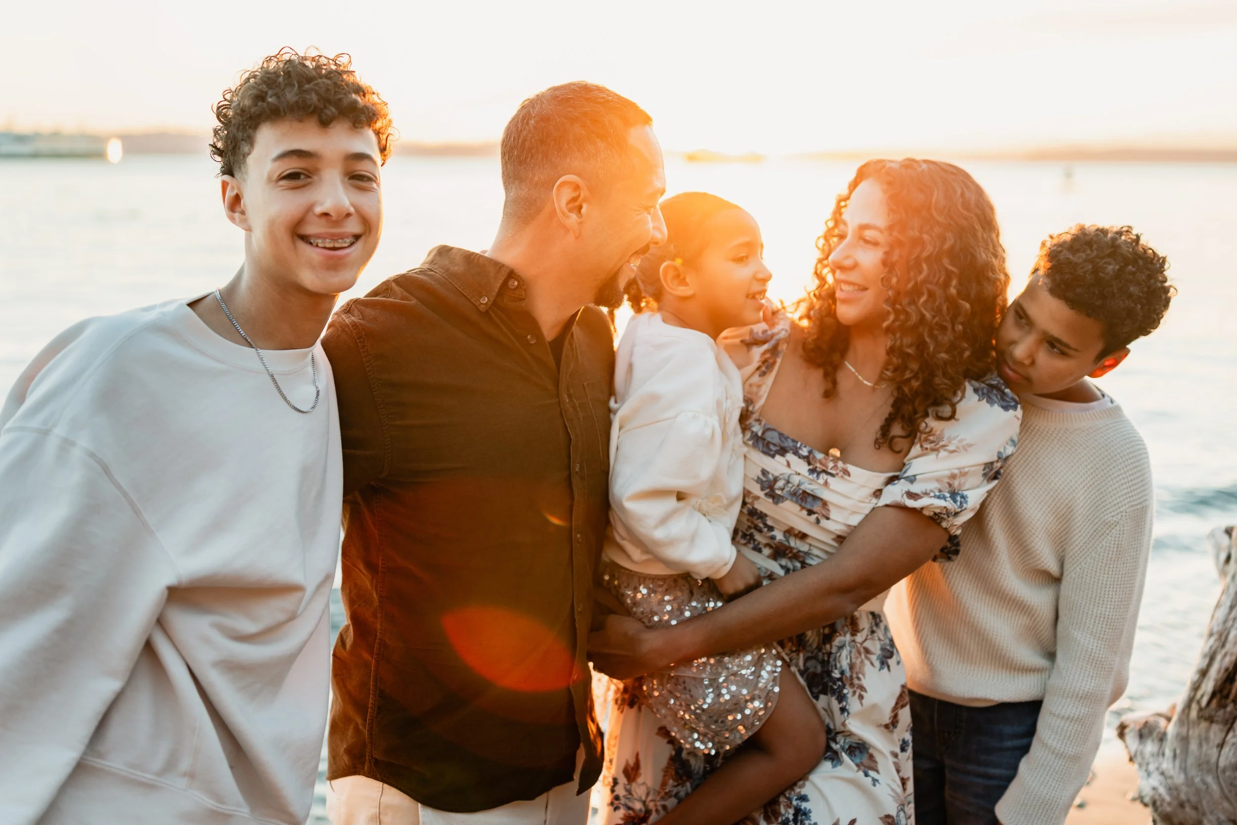 A family of five posing on the beach in West Seattle for a Seattle family photography session at sunset.