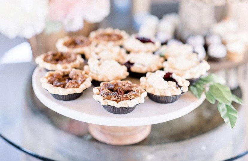Mini tarts with various fillings on a wooden cake stand.
