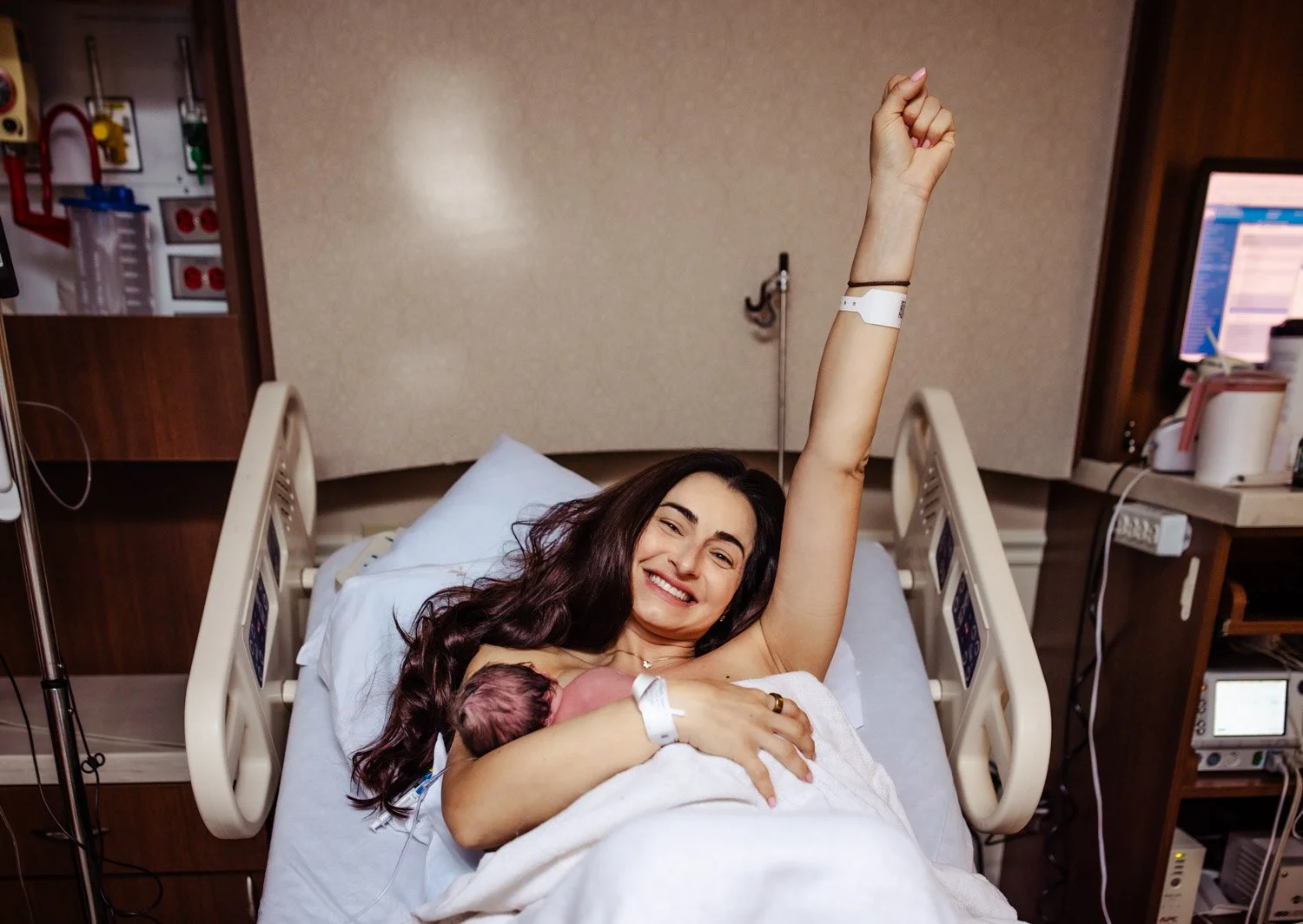 young mother proudly smiles and raises her arm in victory of a successful vbac at boca regional hospital with boca midwifery