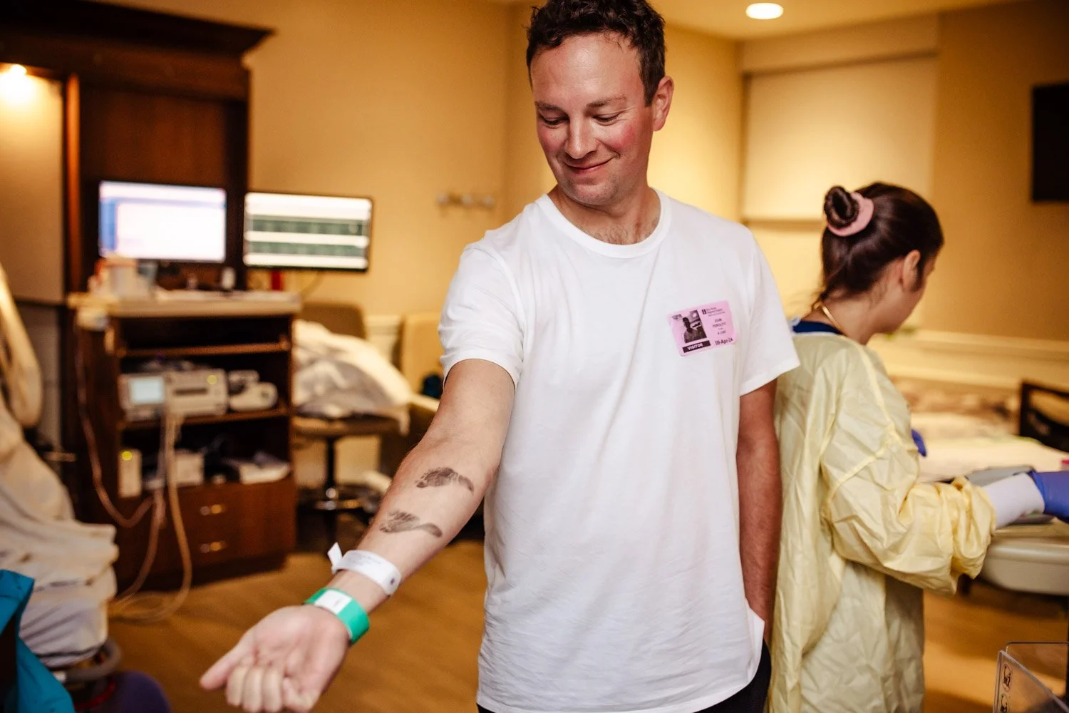 proud new dad shows his newborn baby's inked footprint on his arm in the hospital labor delivery room at boca regional