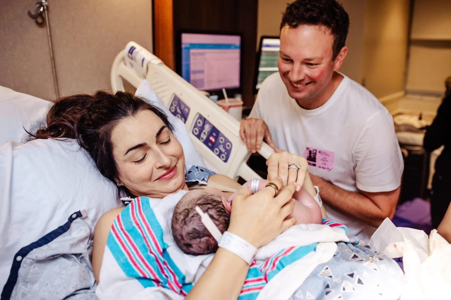 happy new parents hold their newborn baby girl in the hospital bed of boca regional labor delivery