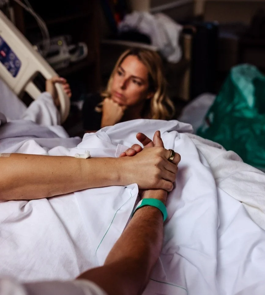 doula gazes as a woman in labor breaths through contraction her husband holding her hand