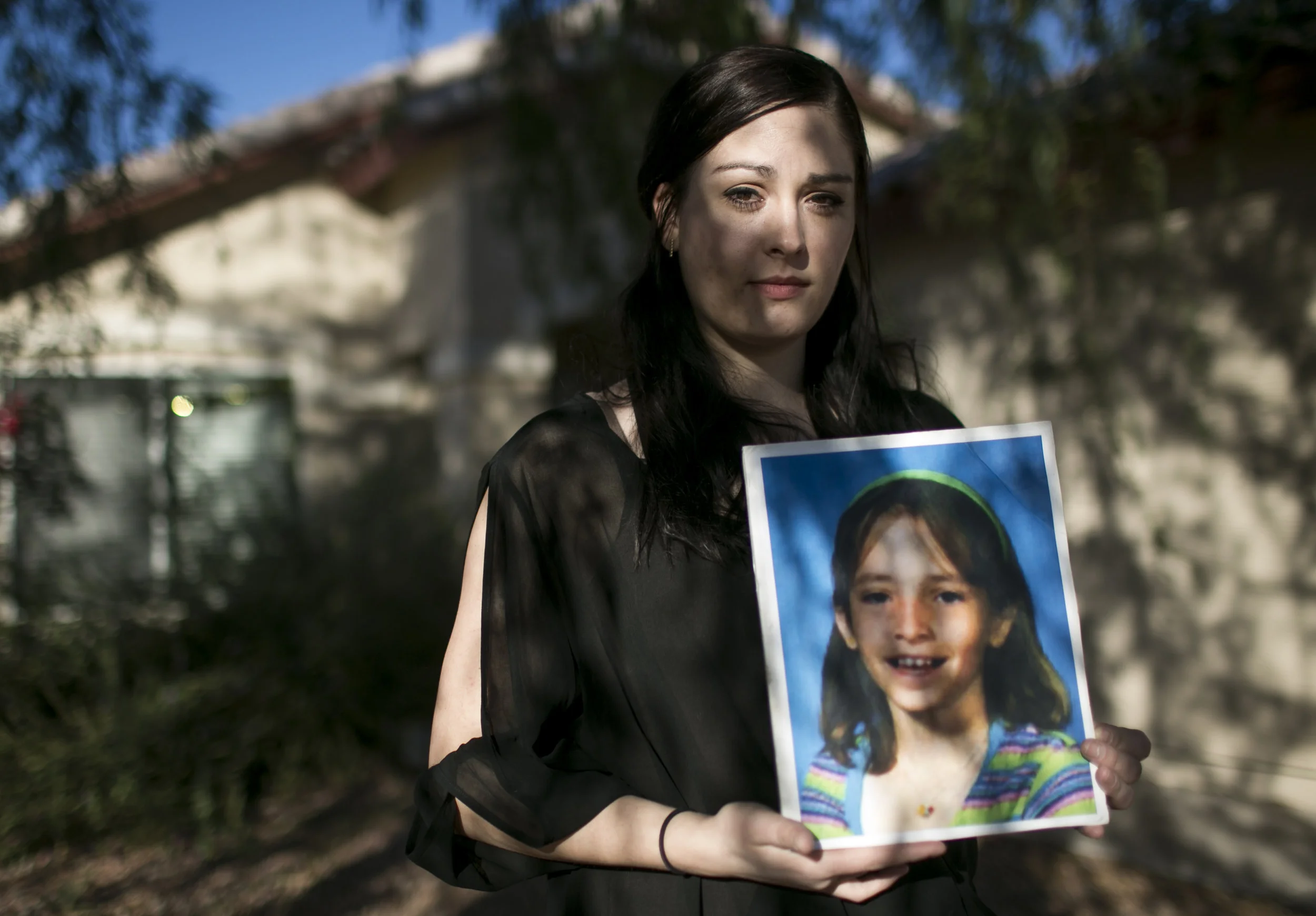  Kimber Biggs stands in front of her home holding a photo of her sister Mikelle Biggs, who disappeared from their Mesa neighborhood in 1999 without a trace.  