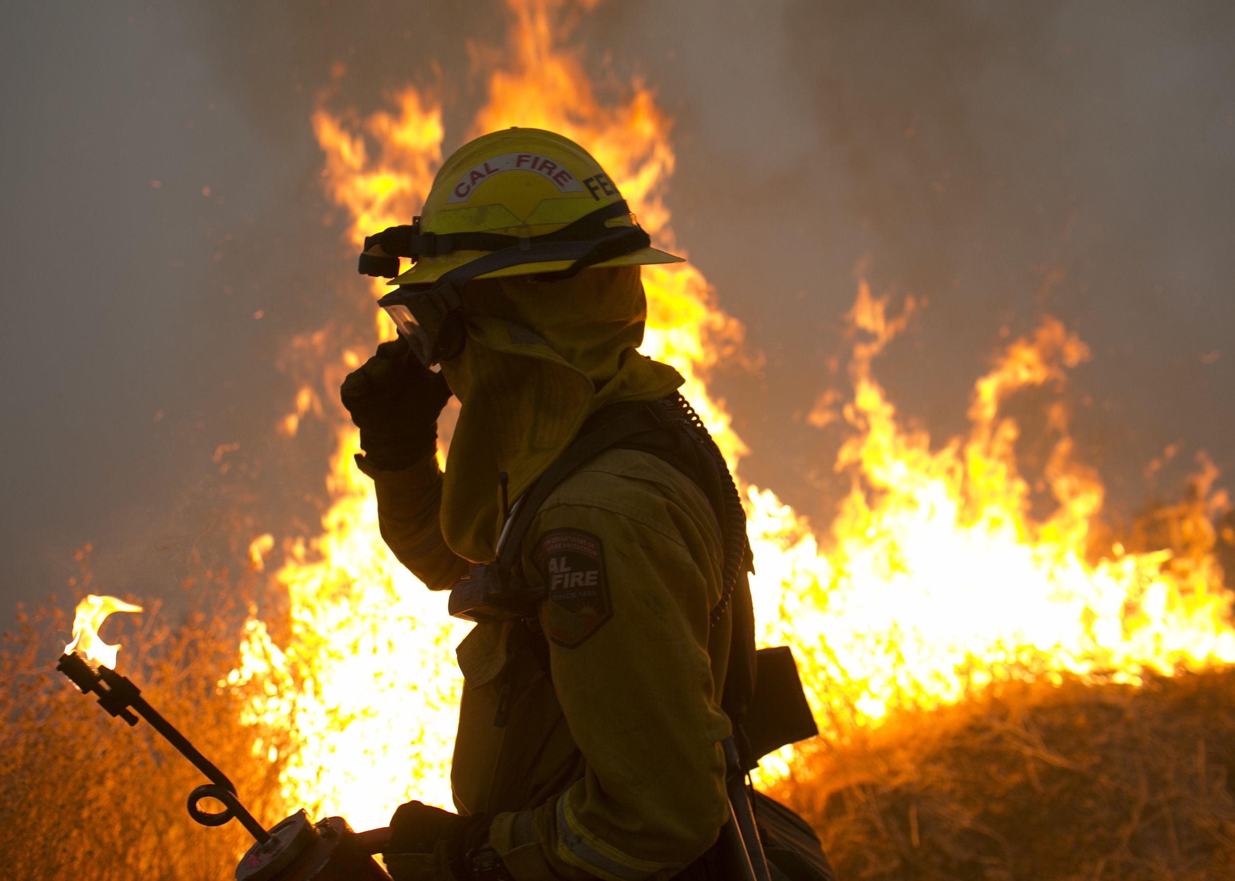  A firefighter with Cal Fire helps to hold a line in the Camp Fire with a control burn Near Bloomer Hill in Butte County in California. 