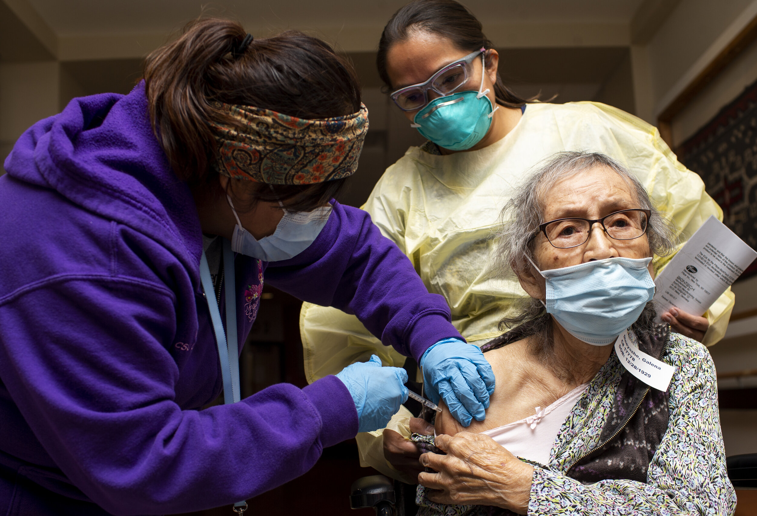  Medical assistant Vangie Yazzie (left) administers the Pfizer COVID-19 vaccine to Galena Dineyazhe (right) as director of nursing Monica Jones (back right) watches at the Dr. Guy Gorman Senior Care Home on the Navajo Nation in Chinle, Ariz. on Dec. 