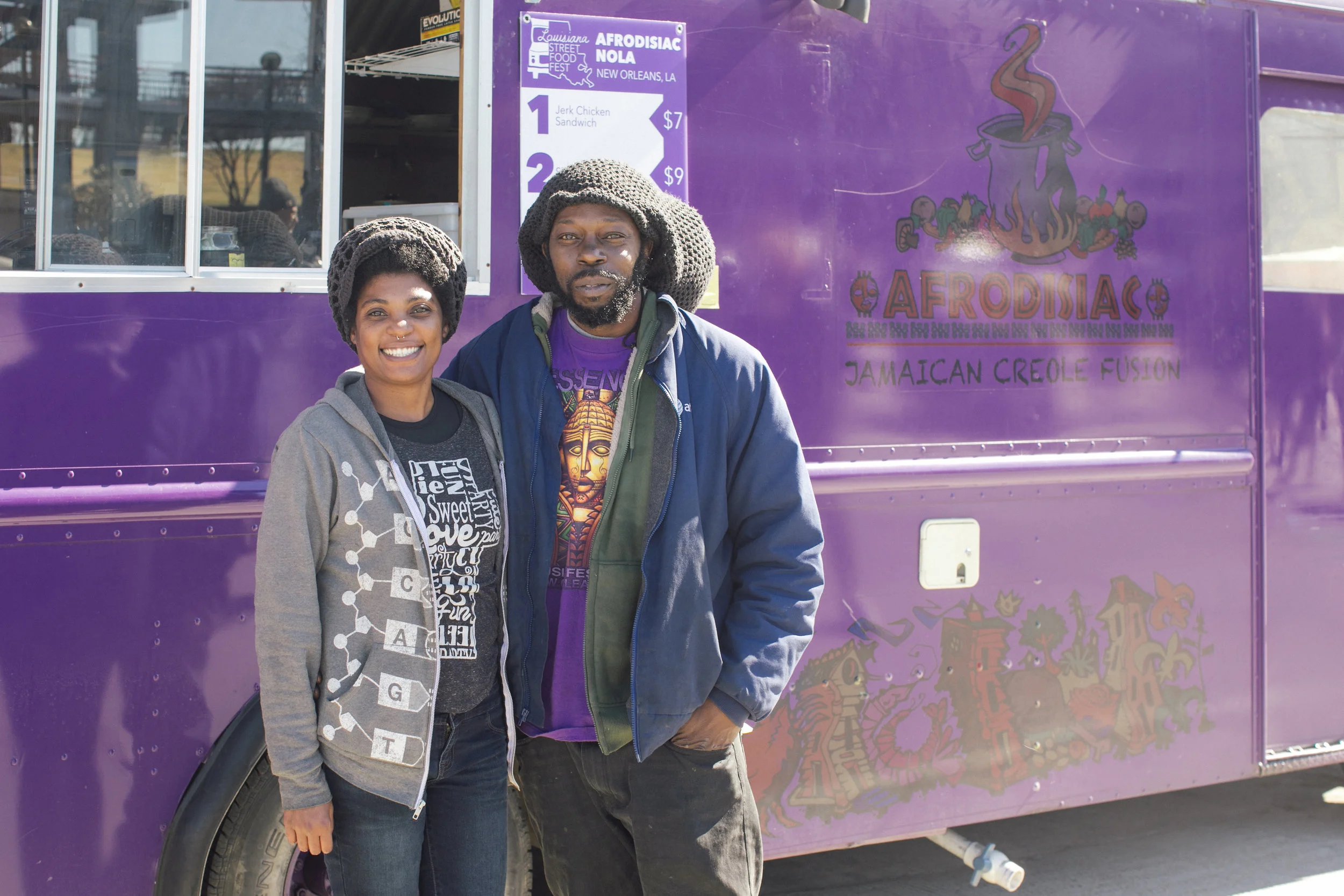 The husband and wife duo behind Afrodisiac NOLA smile in front of their purple truck. Afrodisiac NOLA serves unique fusion dishes combining flavors of Caribbean and New Orleanian cuisine. OA