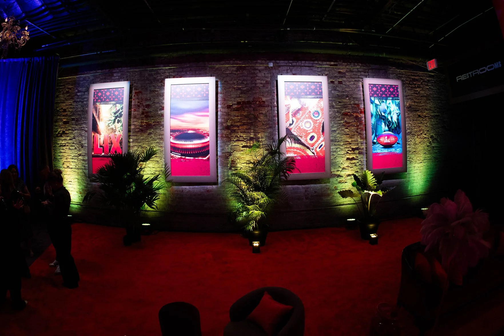 Three illuminated digital displays surrounded by greenery and colorful décor.