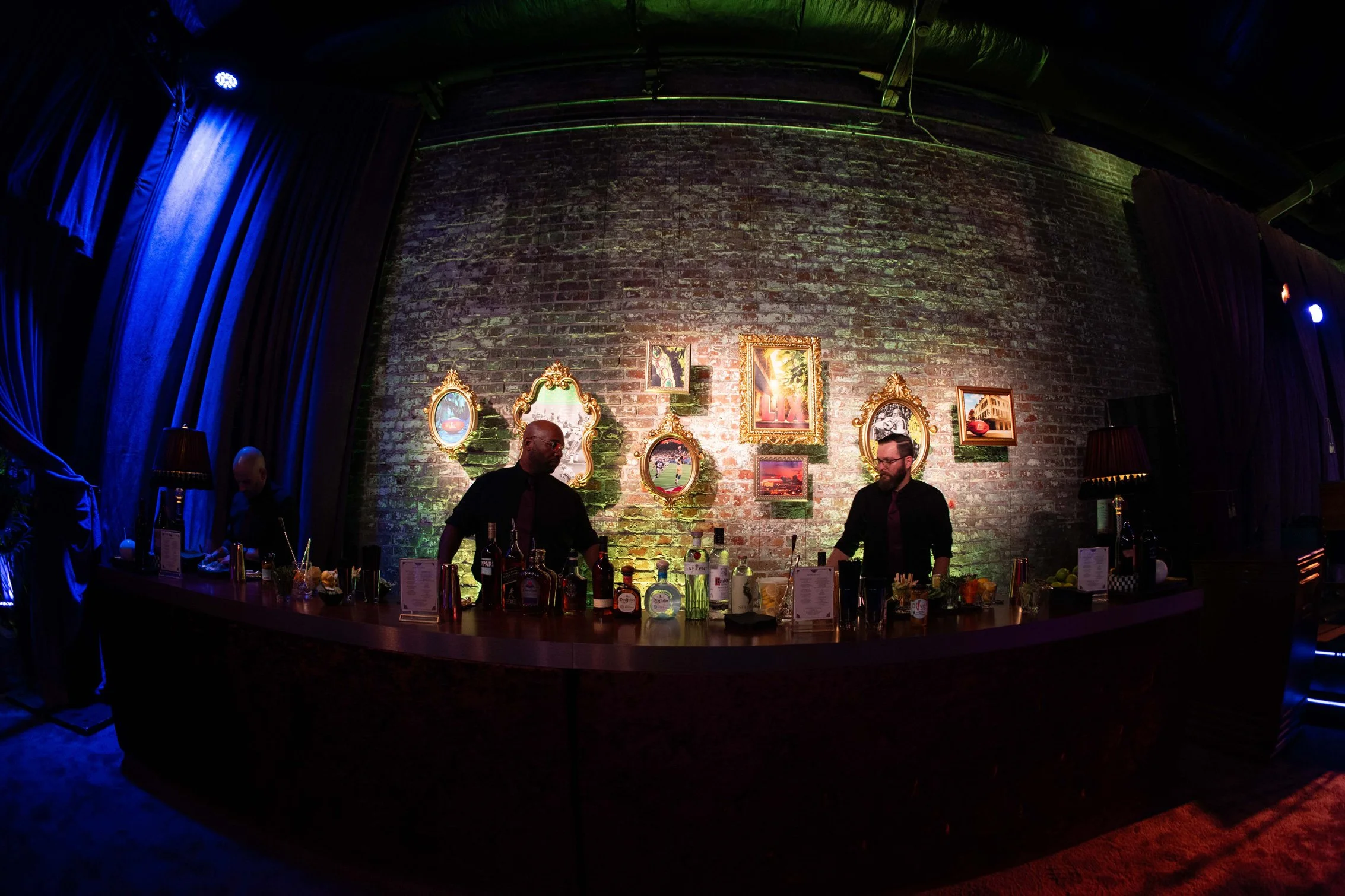 Bar area framed by a greenery wall and colorful artwork.