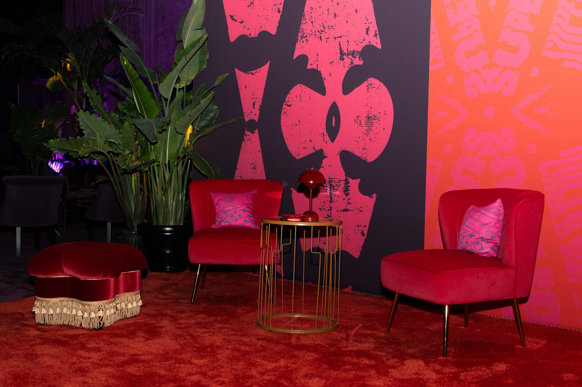 Red lounge area with tropical greenery and graphic wall décor.