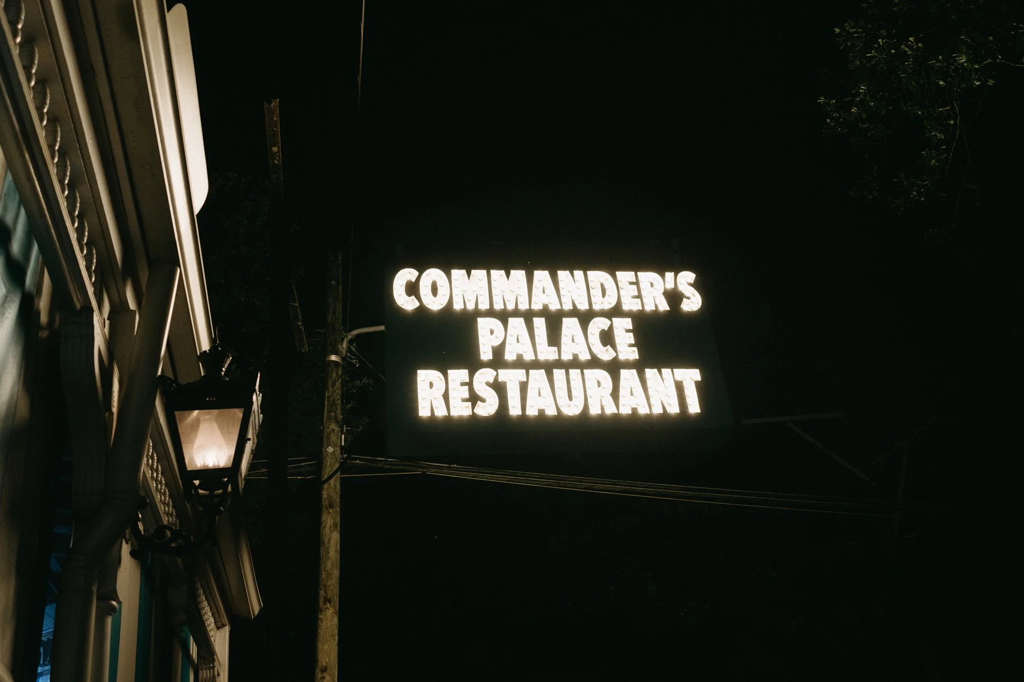 “Commander's Palace Established” sign illuminated at night.
