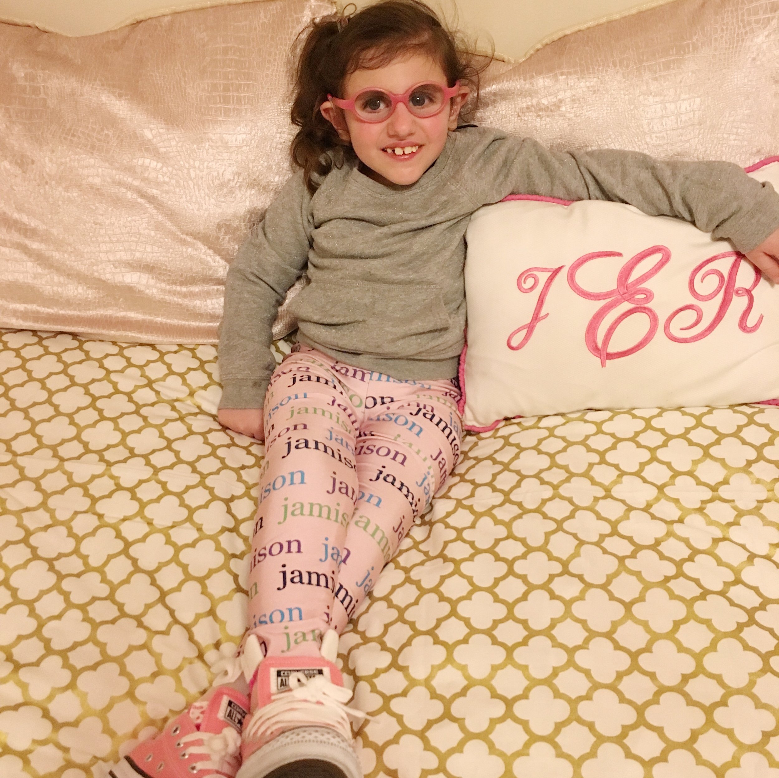 Jamison on her new bed for the 1st time, next to the pillow I monogramed for her as baby.