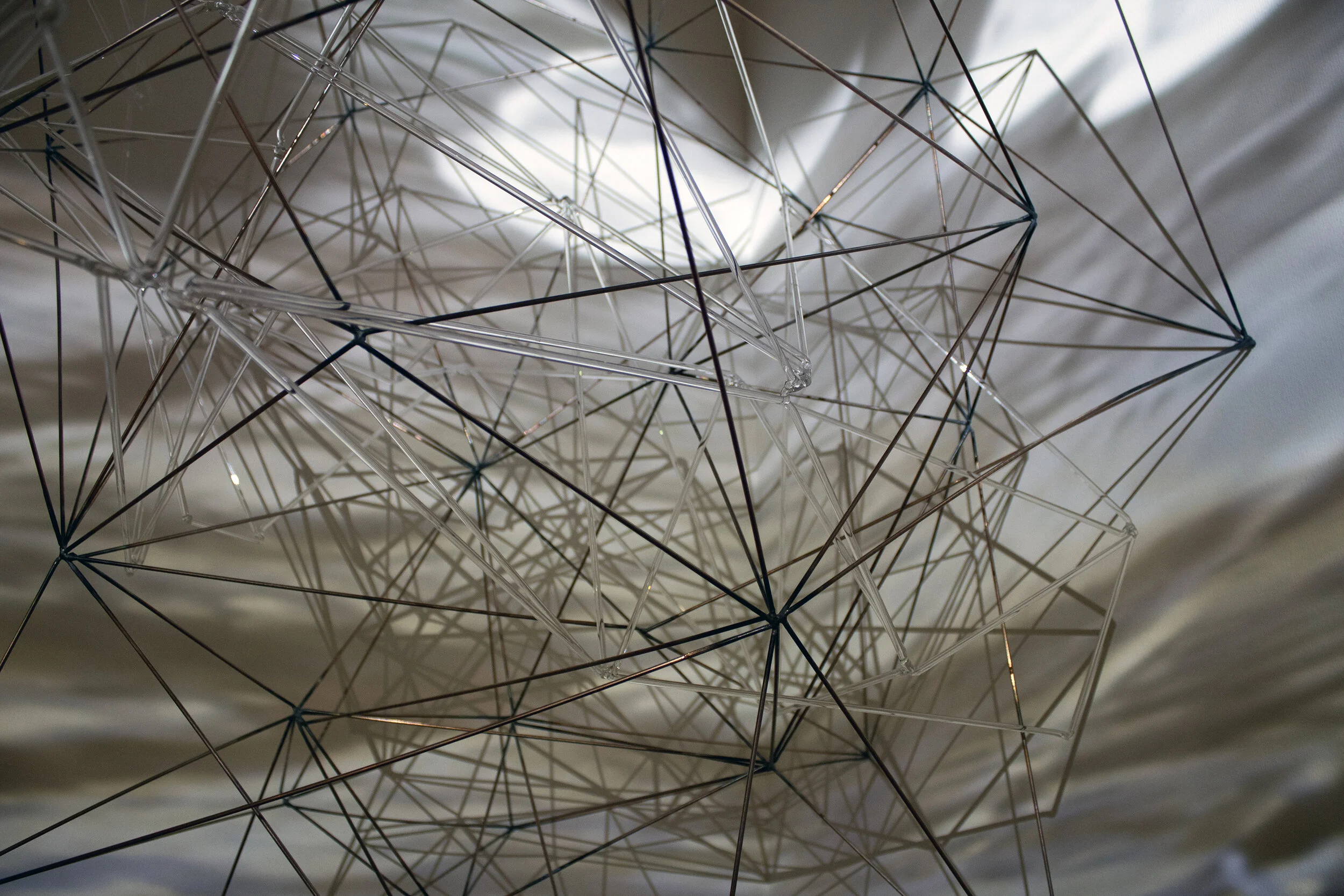 Synthetic Erosion Welding rod, scientific glass rod, projection of ice melt video, 40 x 30 x 43 in., 2021 The sculptural form is derived from the triangulated mesh of 3D scan data. A projection mapped video of ice melting in a stream overlays the sculpture.