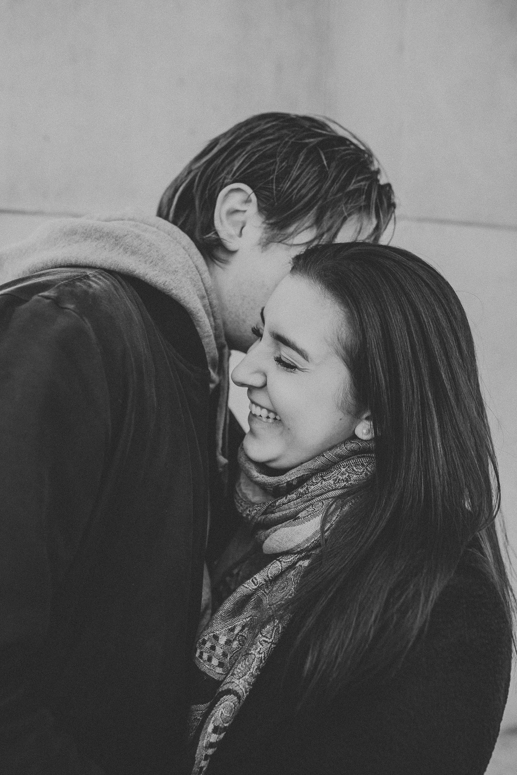 Boy whispering secrets into girls ear and giggling during engagement session in New York City, New York