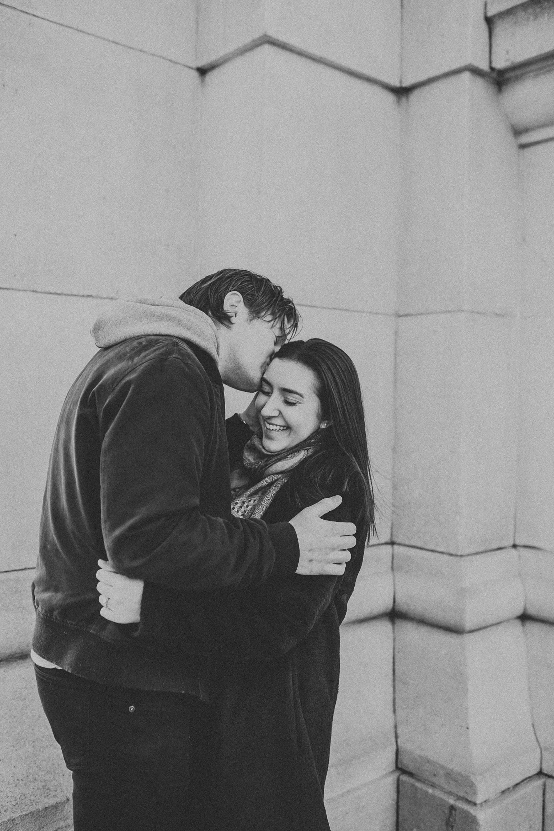 Boy whispering secrets into girls ear and giggling during engagement session in New York City, New York