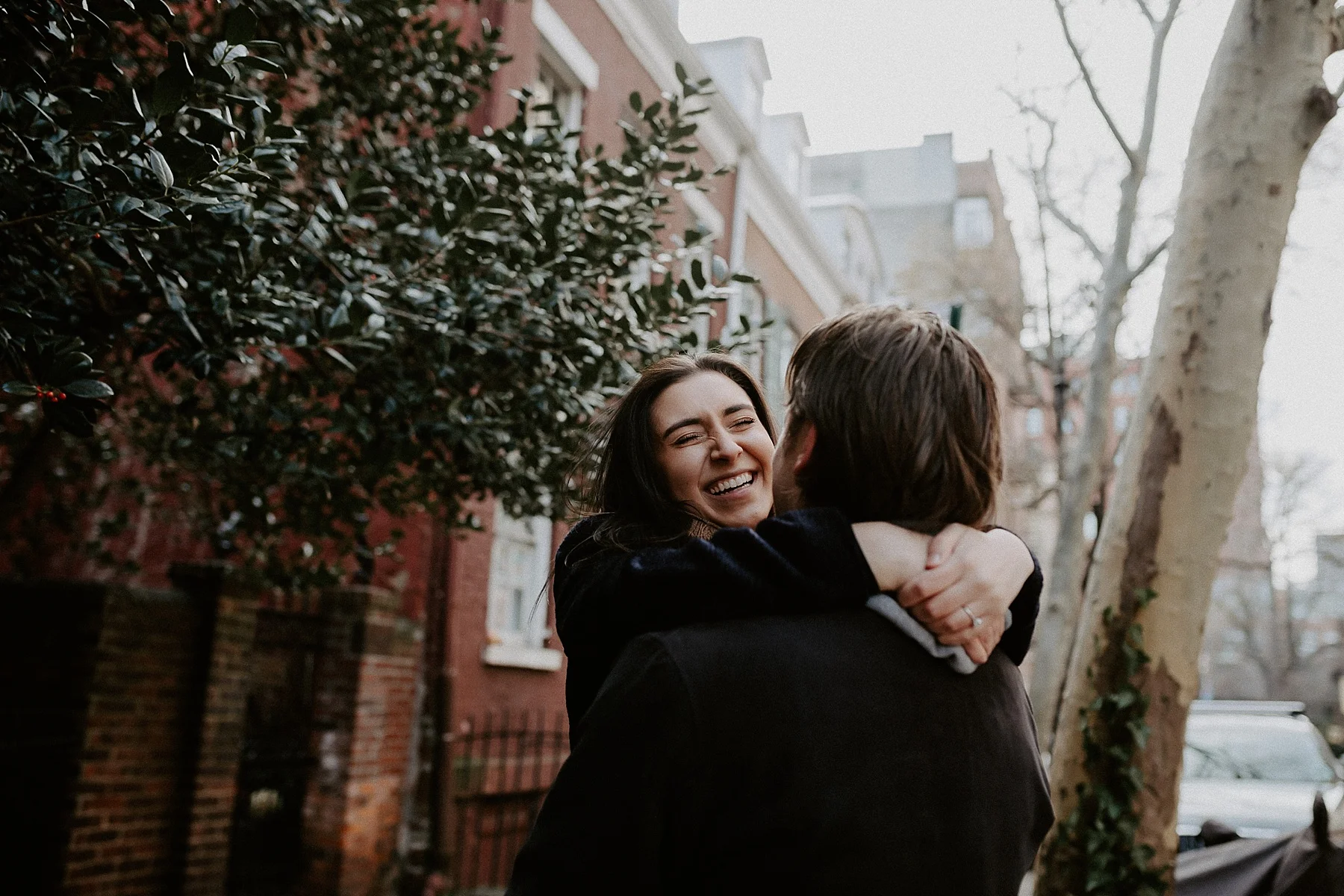 Couple laughing and spinning around in one another's arm on New York City sidewalks in Greenwich Village