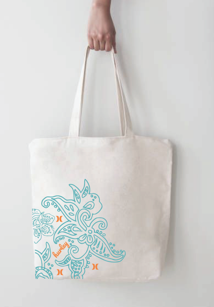 A person holding a white canvas tote bag with blue butterfly and floral designs and the word "hustle!" in orange, hanging against a plain light background.