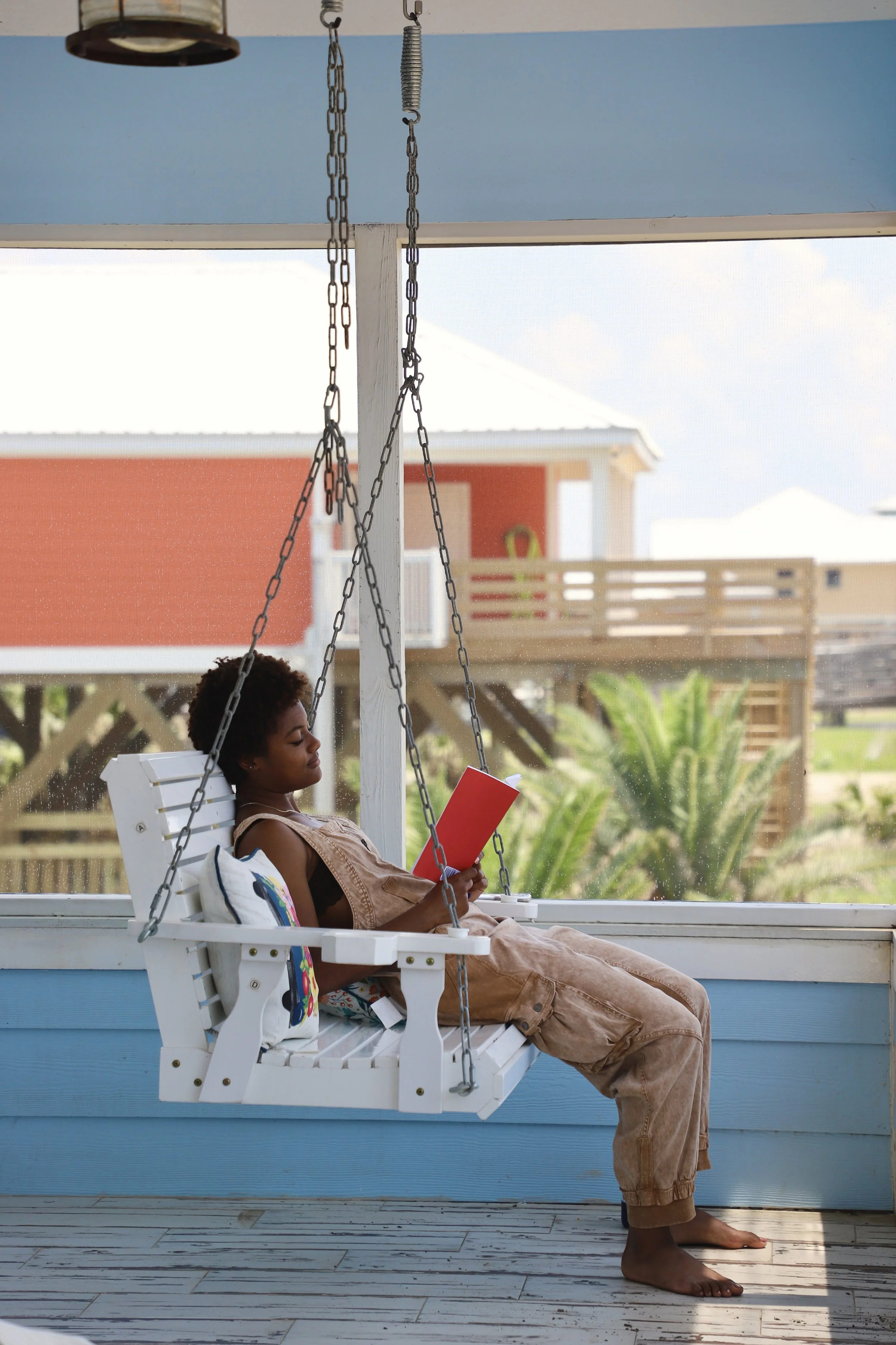  Simone sits on the porch swing in the Grand Isle reading  The Awakening.  The first four days of Bookpacking was spent in a holiday house on the Louisiana coast.  