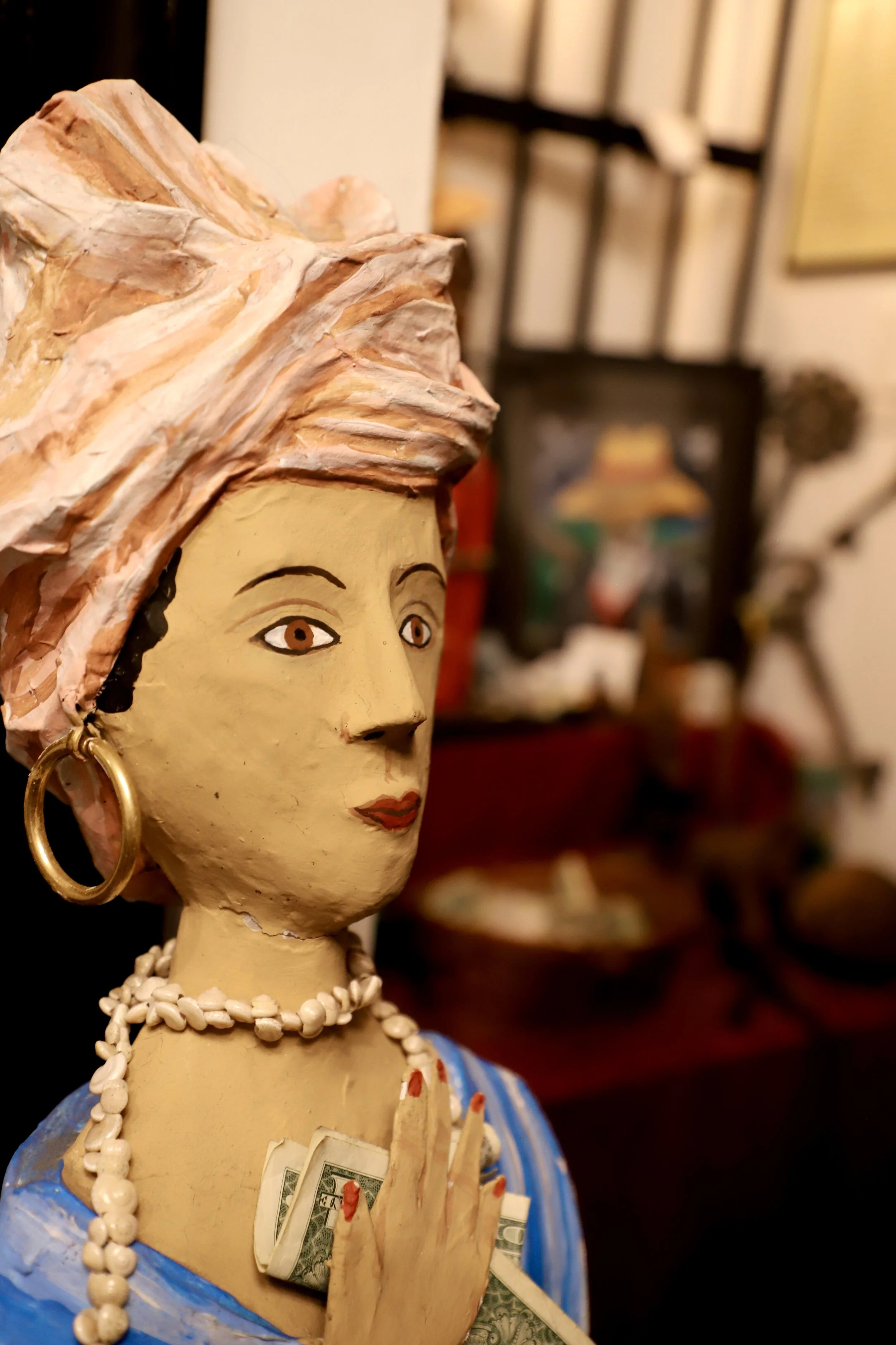  A statue of a diety of the VooDoo Culture stands strong with an offering of a $1 bill. At this point in the book packing explorations, was filled with Voodoo and Vampires. This woman was just one of the many pieces that make up the entirety of the V