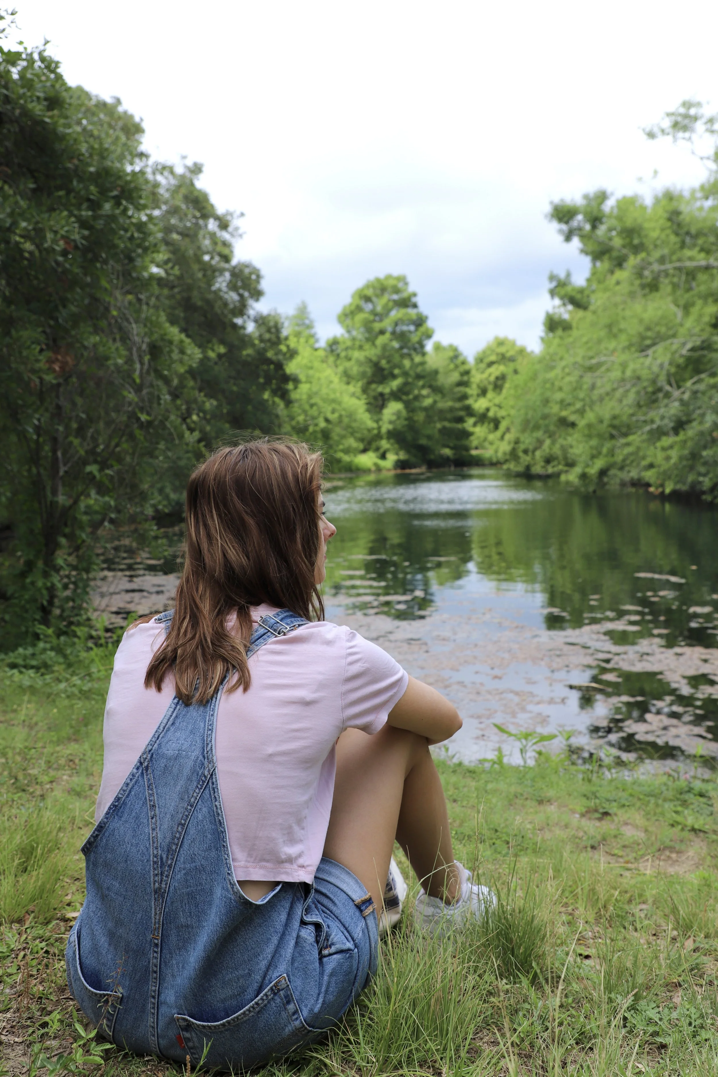  Kamryn sits at the bank of a pond looking out onto the swans swimming by. This was the groups adventure to Audubon Park in which they strolled along the trails and nestled up into a gazebo for their seminar.  