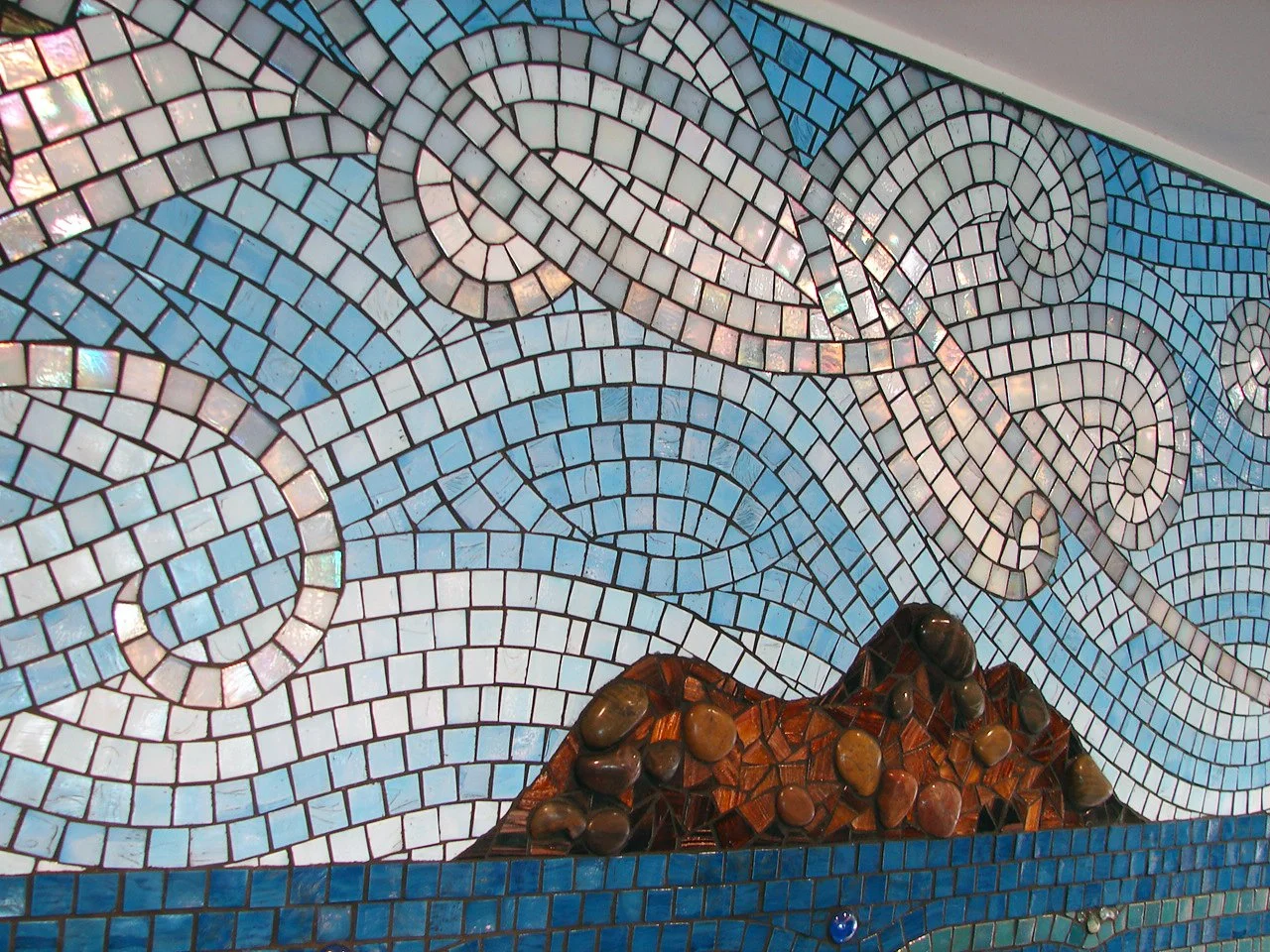 Detail of Mokuluas Islands mosaic backsplash showing iridescent white cloud swirls and the Mokuluas Islands rendered in glass and pebble stones