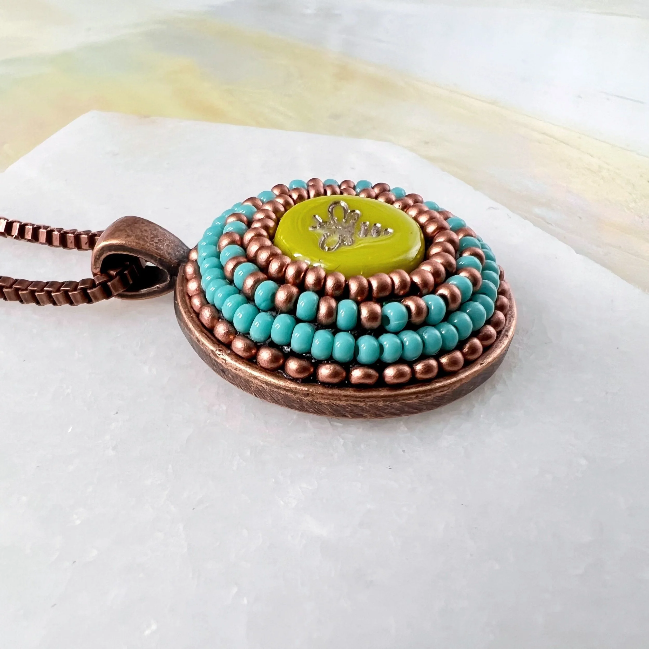 Side view of bee mosaic pendant by artist Dyanne Williams.