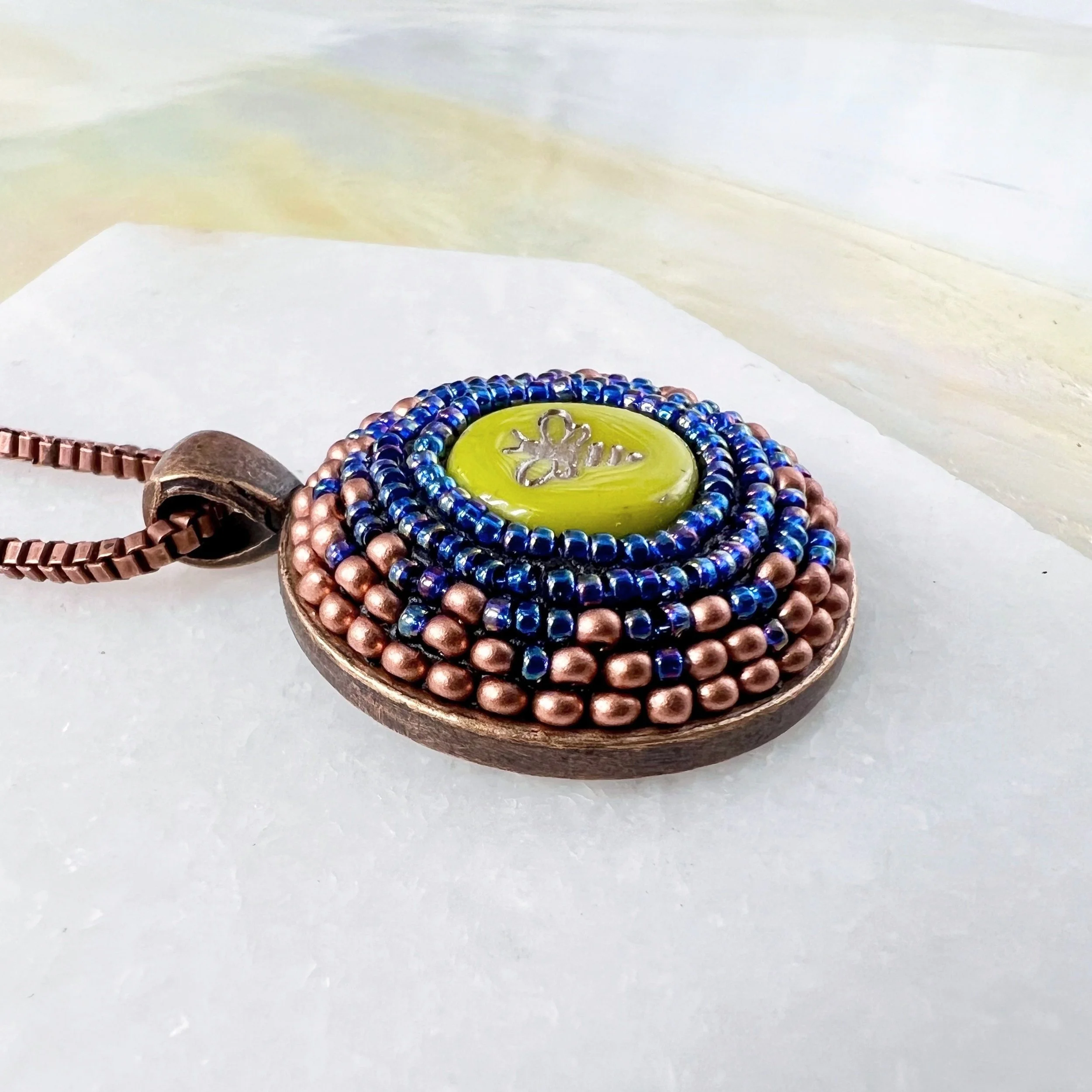 Side view of bee mosaic pendant by artist Dyanne Williams.