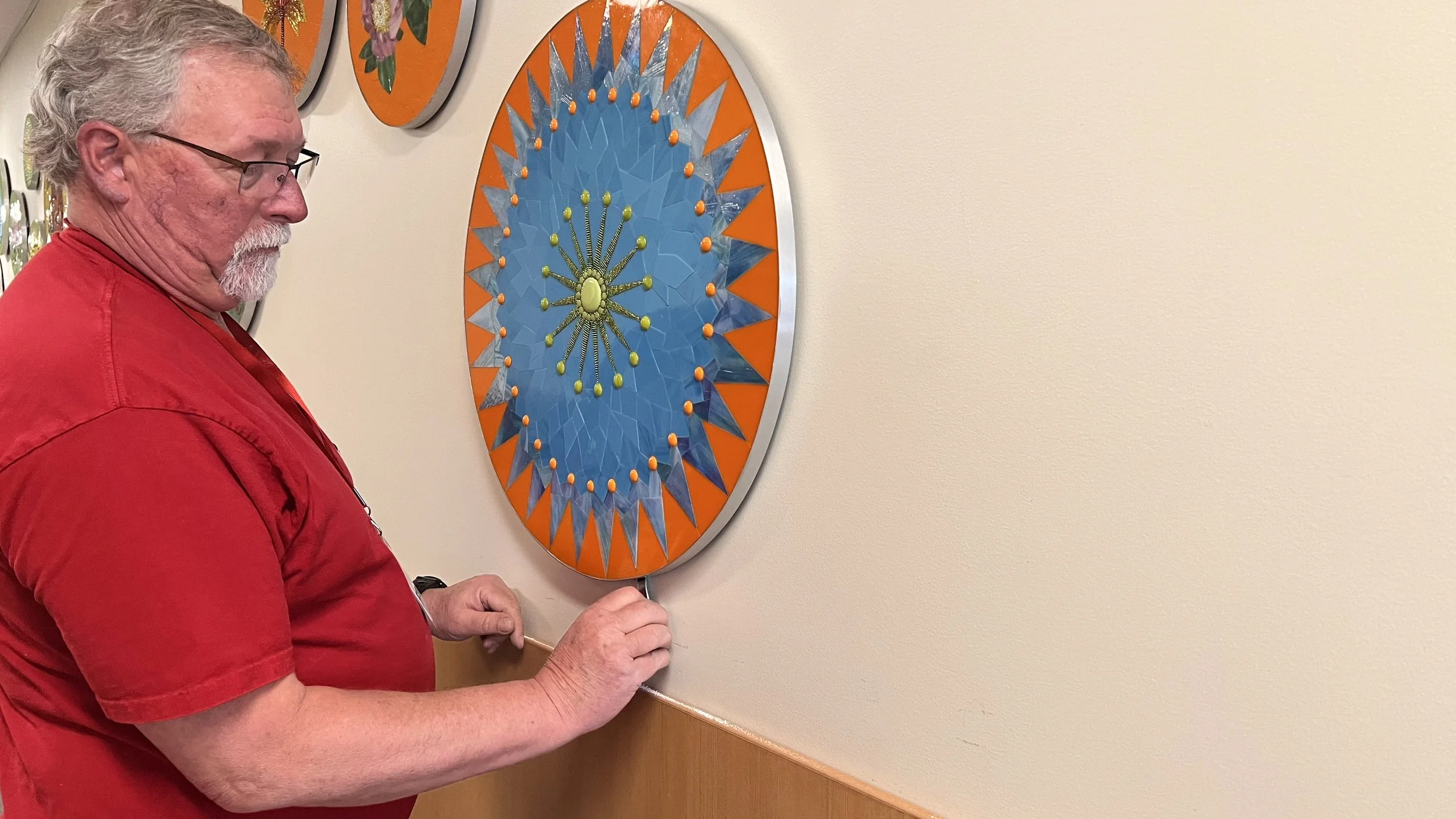 Head custodian using a wrench-like key to lock the security hanger on a Cycles public art mosaic panel at Ida Nason Aronica Elementary School in Ellensburg, Washington