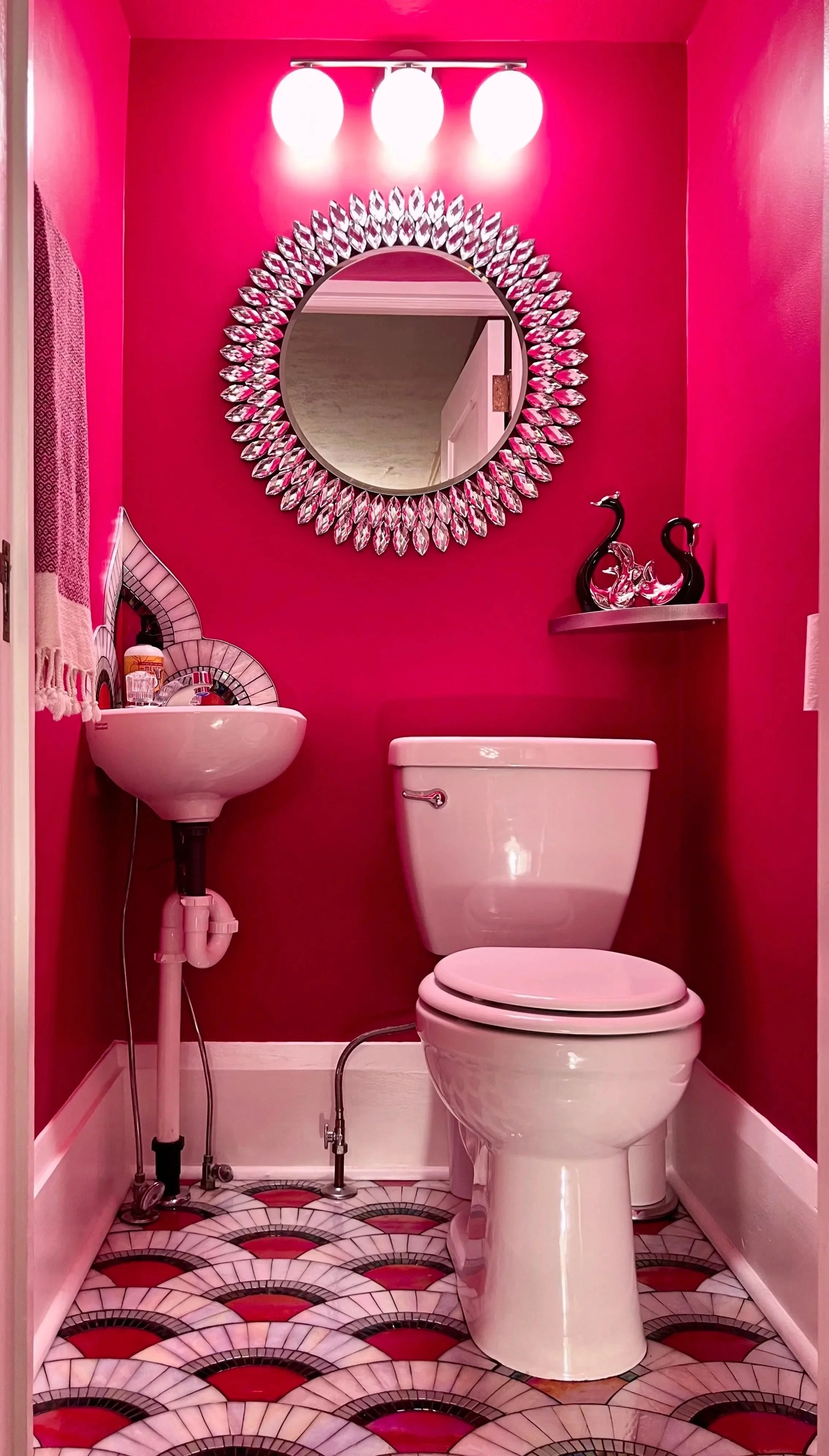 Art Deco mosaic powder room showing magenta painted walls and ceiling, scallop mosaic floor, brushed nickel vanity light, and crystal mirror