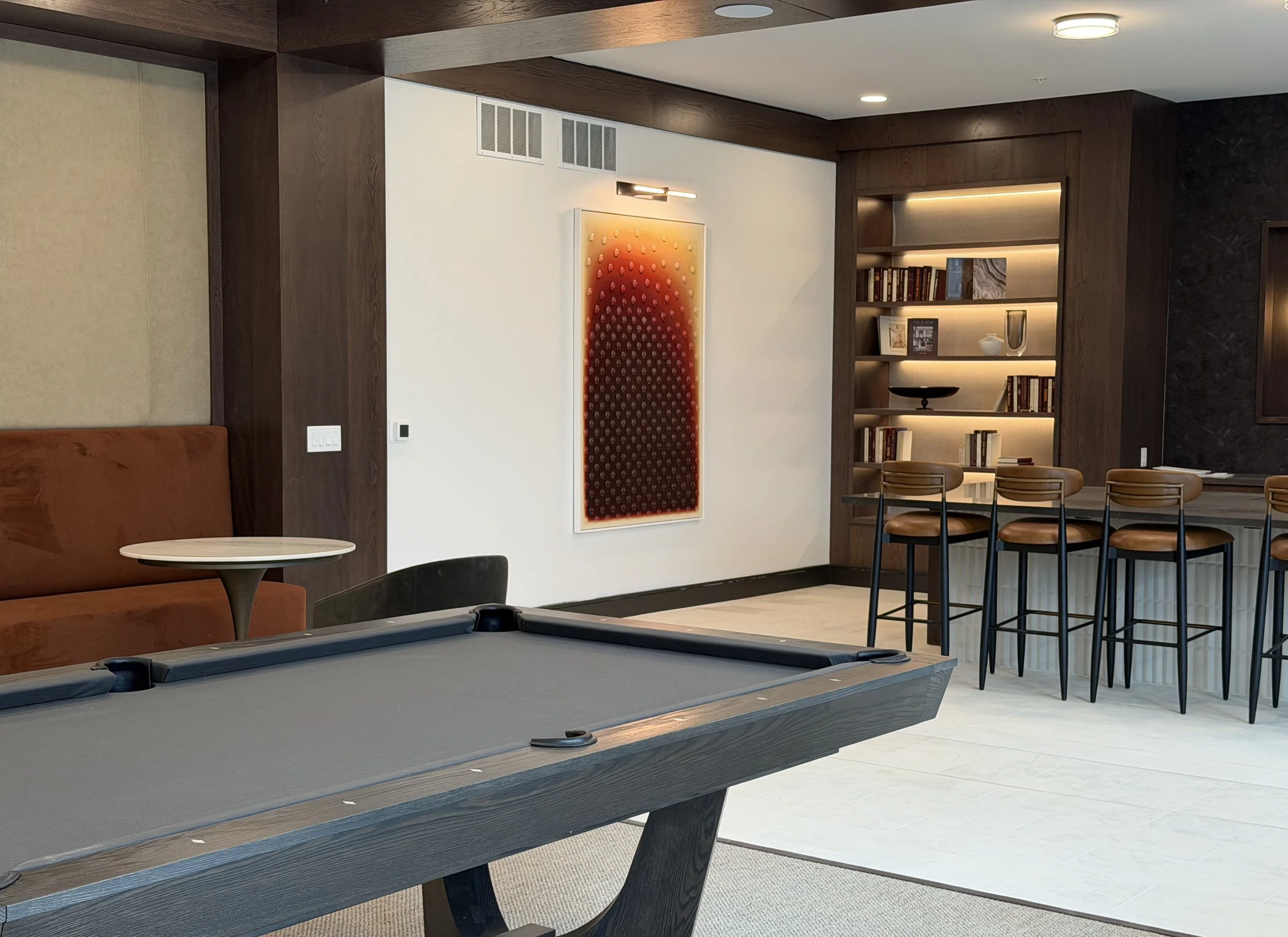 Aura I Cabochon Painting by Dyanne Williams installed at Tempo at Truepointe, Columbus Ohio, illuminated by picture light showing glass cabochon texture and brown-red to cream gradient