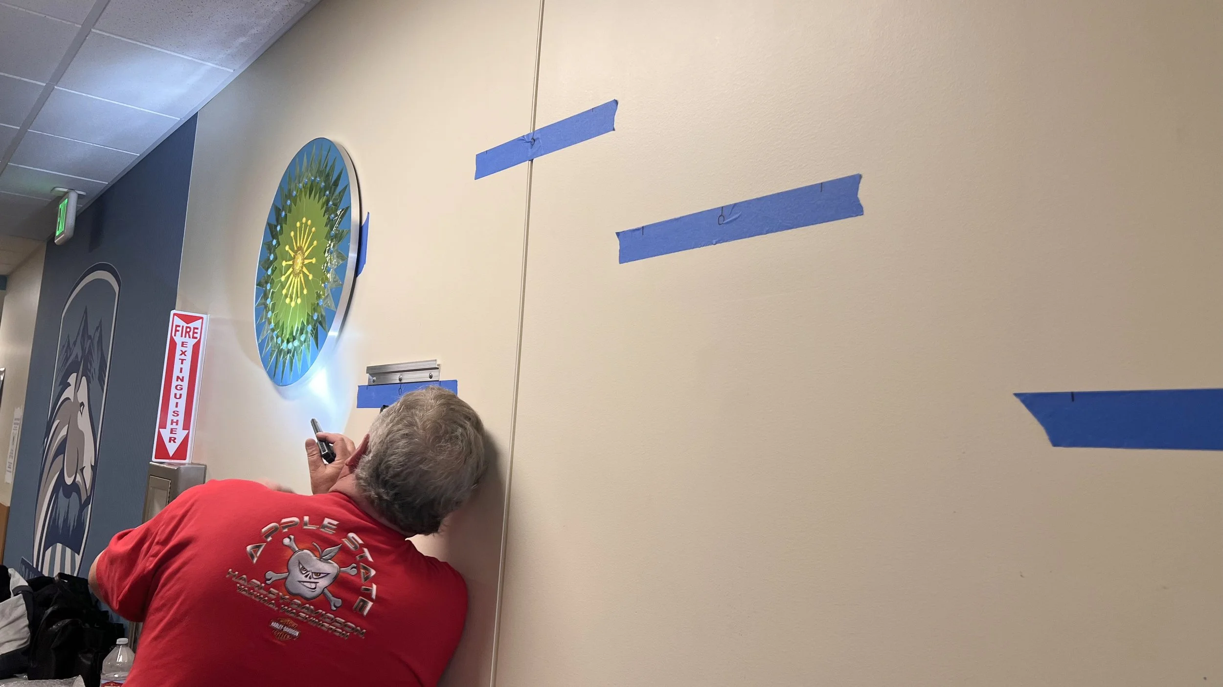 Head custodian inspecting the first installed Cycles public art mosaic panel at Ida Nason Aronica Elementary School in Ellensburg, Washington