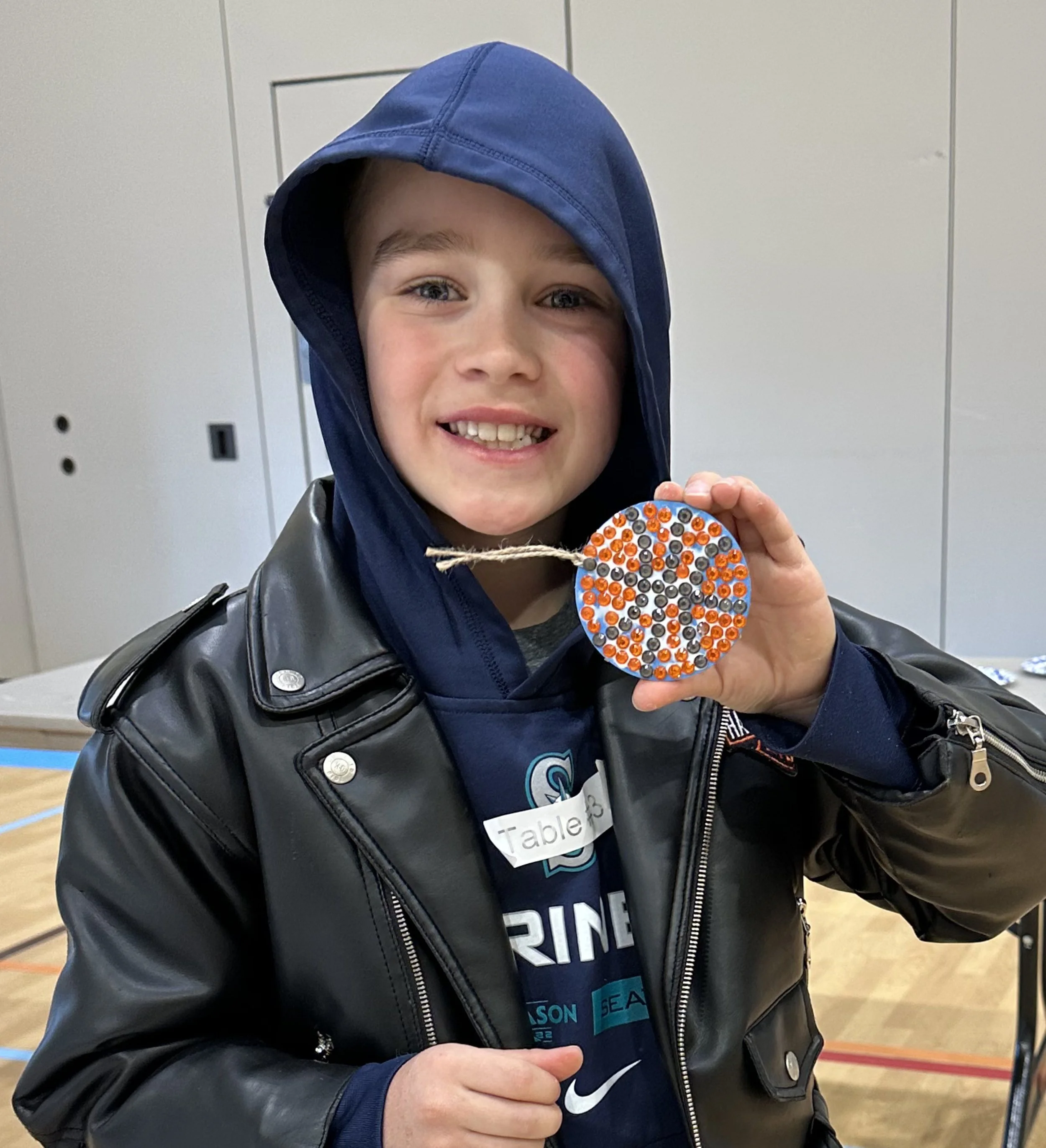 Student proudly displaying his completed basketball gem mosaic medallion from the Cycles public art commission participation project at Ida Nason Aronica Elementary School in Ellensburg, Washington