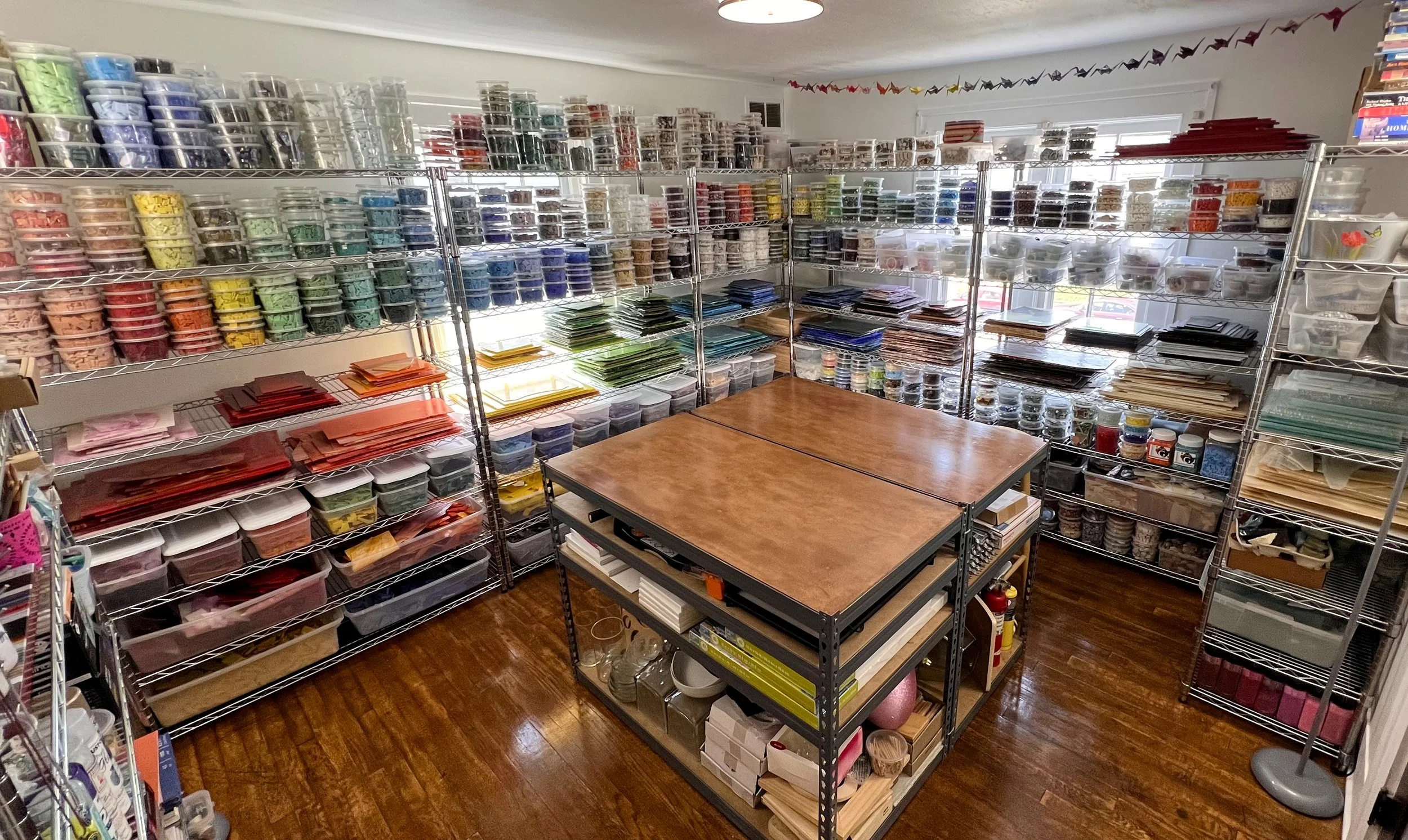 Dyanne Williams' glass room studio with organized stained glass sheets and supplies for mosaic art creation