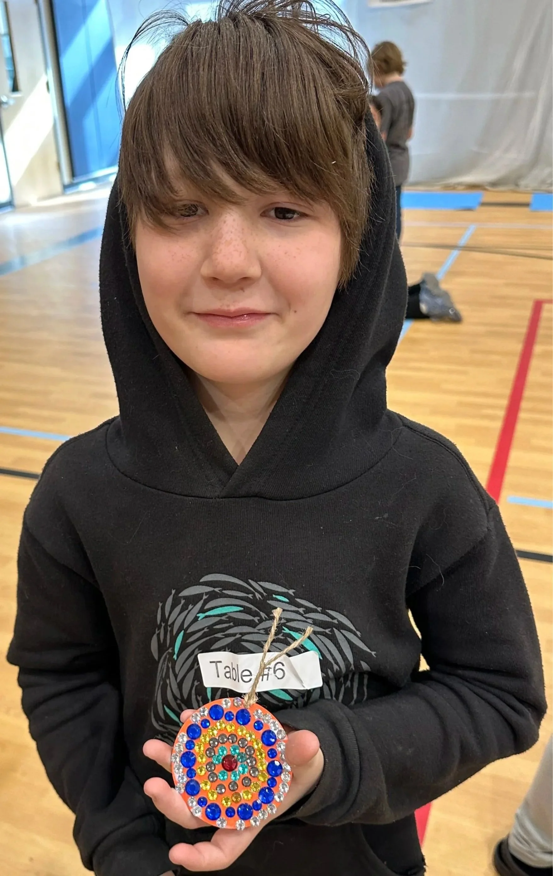Student proudly displaying his completed gem mosaic medallion from the Cycles public art commission participation project at Ida Nason Aronica Elementary School in Ellensburg, Washington
