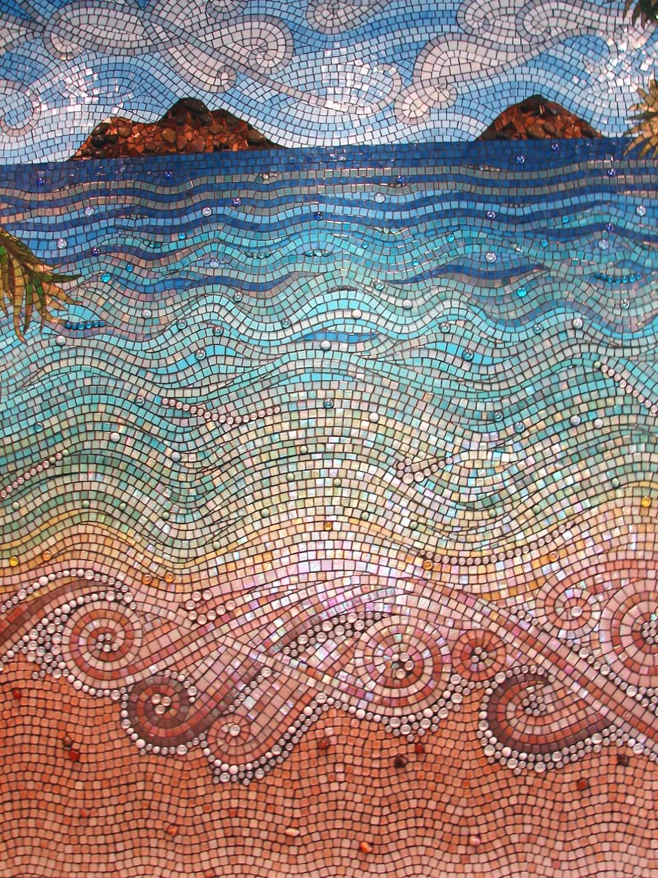 Detail view of Mokuluas Islands mosaic backsplash showing ocean panorama with clouds, Mokuluas Islands, palm fronds, waves, and decorative spiral sand patterns